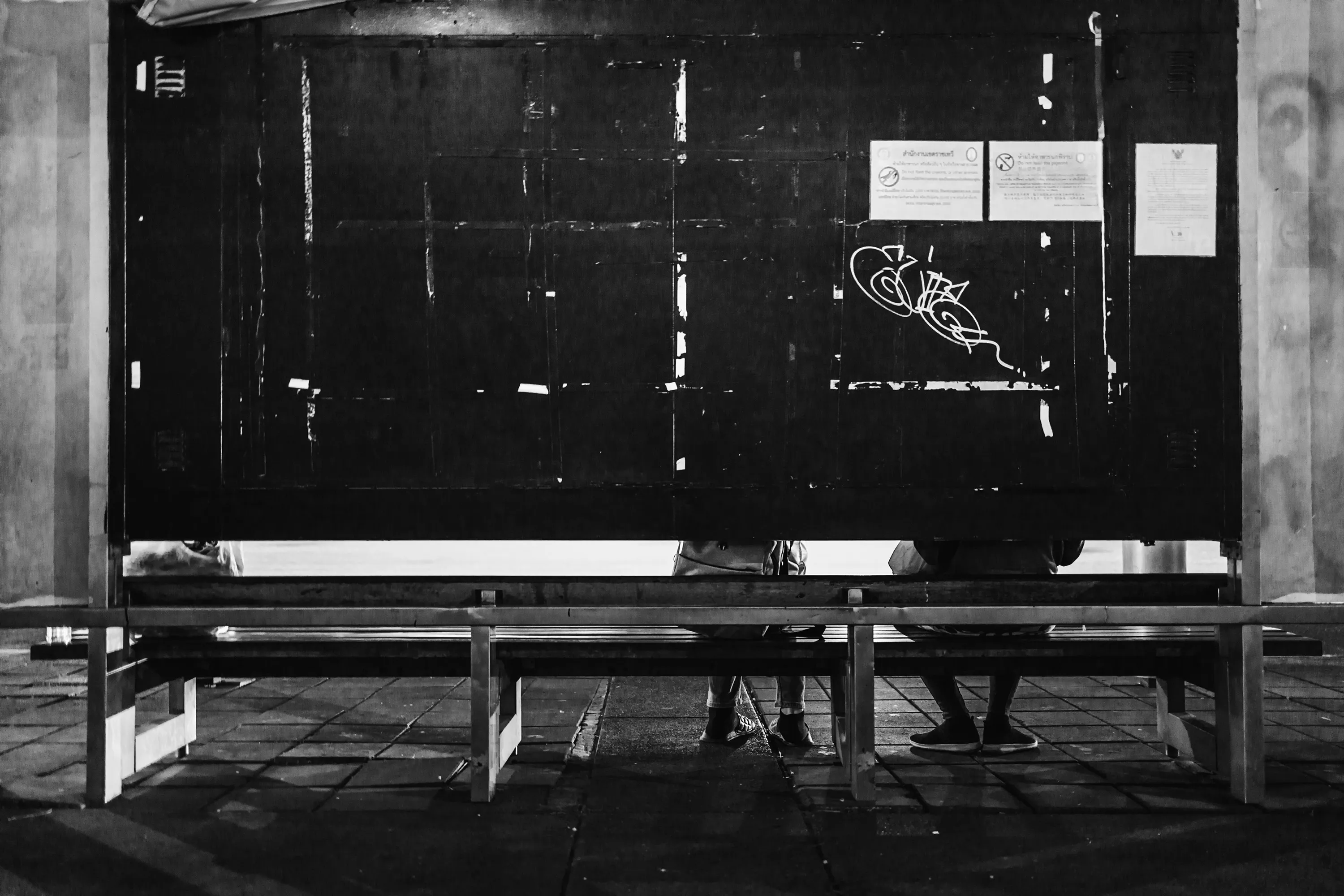 Beacon
The Sea #18

// The inception of the Beacon series traces back to a solitary photograph captured for the project "Portuguese Sea" by Bernardo Caria. Rooted in Fernando Pessoa's 1922 poem of the same title, the project delves into diverse interpretations of home. At its core, the sea symbolizes a wellspring of inspiration, exploration, and identity.

A year later, the poetic essence of Pessoa's verses metamorphosed into a lens-based art series titled Beacon. The expansive sea embodies boundlessness and promise, a stark contrast to the confines of urban living, particularly within sprawling megacities. Amidst the bustling metropolis, where individuals often feel lost amidst concrete canyons and a cacophony of noise, finding the tranquility Pessoa seeks in the sea proves elusive.

Yet, within the urban labyrinth, a languid light unveils the unseen and overlooked. Neon emanates from forsaken bus stop billboards, casting an ethereal glow reminiscent of coastal beacons. This luminous voyage through the cityscape evokes the hues of the sea—rugged and brilliant, evoking a longing for home. The tales of those setting out on their journeys remain shrouded in mystery to us; we merely glimpse them as they wait or vanish into the distance. It's only the illumination of the bus stop that hints at a narrative, leaving us to conjure the story within our imaginations.

Adding another layer to the series, documenting the fading Bangkok bus stops adorned with colossal backlit advertisements becomes a testament to identity and transition. As 2024 unfolds, these iconic structures are gradually supplanted by more economical and utilitarian counterparts, signaling an era's end.

At the core of the Beacon series lies photography, offering a distinctive 360º narrative journey that encompasses different media, presented in three parts - The Coast (mixed media), The Sea (photography), and The Wave (collectors reward airdrops) for, “Narratiff” with Colonna Contemporary.
