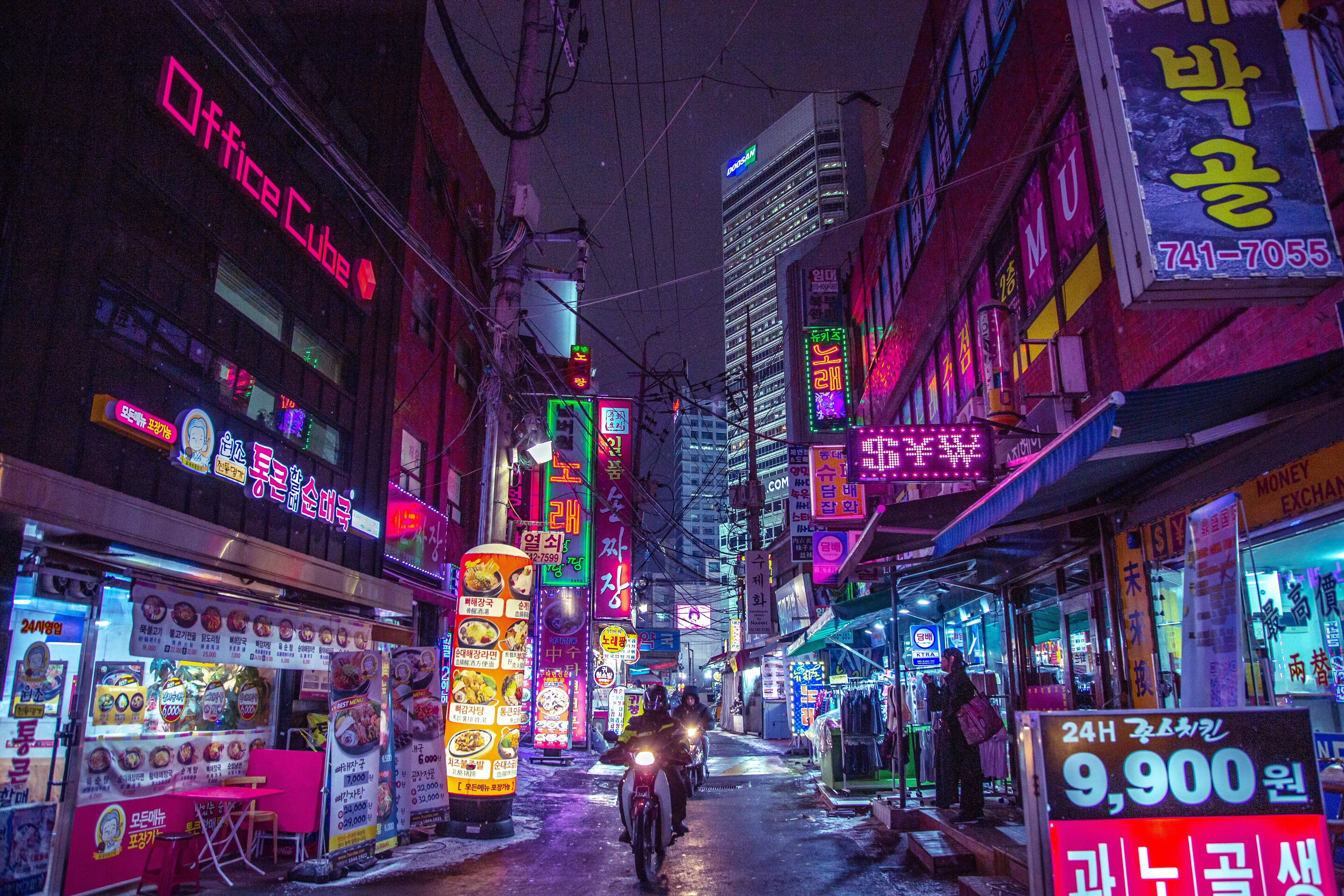 Walk along the gritty streets of Seoul and you will inevitably come across marketplaces every few blocks. It seems every neighborhood has a place of its own, where you needn't walk so far to obtain what you need.
	What I love about these places is the combination of lights and grit, reflecting a very neon-noir vibe and motorcycles delivering goods every few seconds. You can get lost wandering every corner of the marketplace and taking a look at all the clothes, food, and contraptions that the sellers have to offer.
	This marketplace, in particular, has a little secret, it is open 24 hours. The buildings in the background are popular tourist destinations and offer both indoor and outdoor shopping. So whether you prefer the up and personal grit of the outdoors, or the tech and savvy indoor shopping, there is a little something for everyone at any time of the day in Dongdaemun.