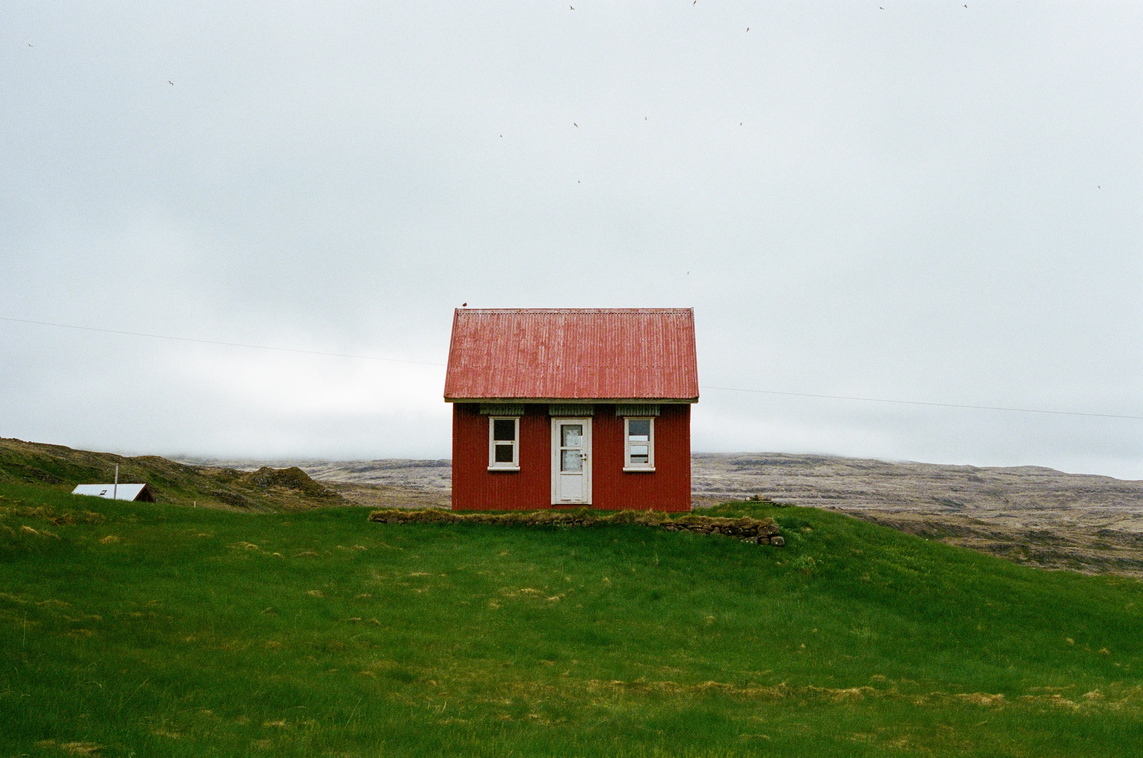 En route to hopefully see some puffins from a gigantic cliff out in the Wesfjords of Iceland, we passed through a small town. A little red house caught my eye. With birds flying overhead, and a cold wind blowing, I grabbed my 35mm camera and took this shot.
