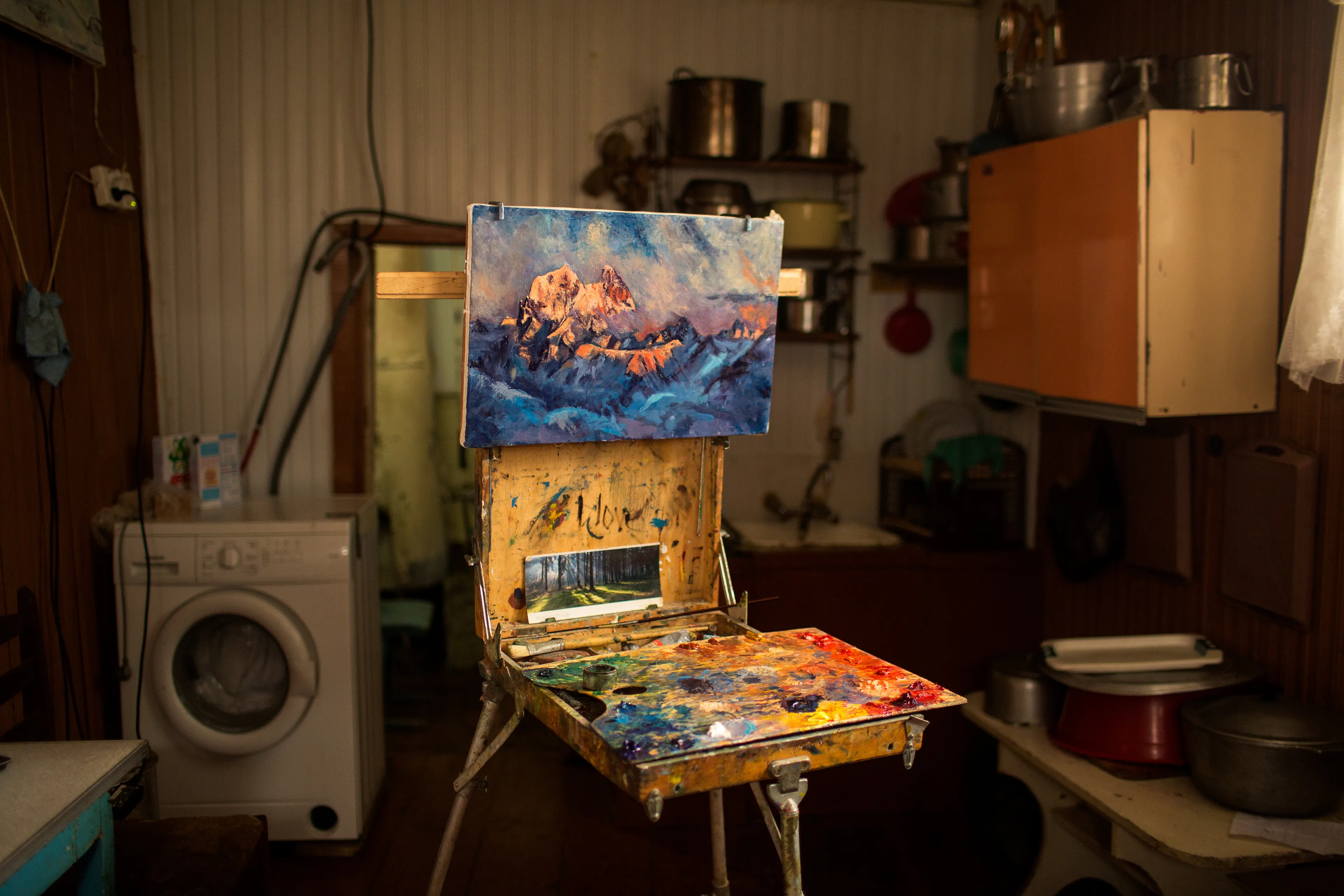 Misha Mchedliani's painting of Mt. Ushba in his kitchen in Mestia, Svaneti, Georgia.  High in the mountains of Georgia, between the breakaway republics of Abkhazia and South Ossetia, in a valley surrounded by 5,000-meter peaks, is Svanetia (Svaneti). The old men of this valley told me that the Svans are the descendants of Sumerian slaves that escaped their bondage and fled north to the Caucasus, where they worshiped the sun god Lile’. Because of this, in all my journals, I called them: “The Children of the Sun.” I stumbled into Svaneti with a hand drawn map and a handful of slide film, and no vision for storytelling, in 1998. But over the course of 107 rolls, taken in three journeys over three years (from 1998-2000), I learned to see. The result was my first photo story, and one that would lead to my career as a National Geographic photographer. Sixteen years after that first journey, National Geographic sent me back on assignment to find my family again, and to create a feature for the magazine. This photo was made on that return journey in the Mchedliani kitchen where I spent many weeks in conversation with my guide and his family.  Ushba was such a dramatic mountain and felt like the centerpiece of Svaneti for me.  It appears in so many of my images from this place.  I remember hearing the stories when I first arrived that this was the rock where Prometheus was chained!   6000  ×  4000 pixels