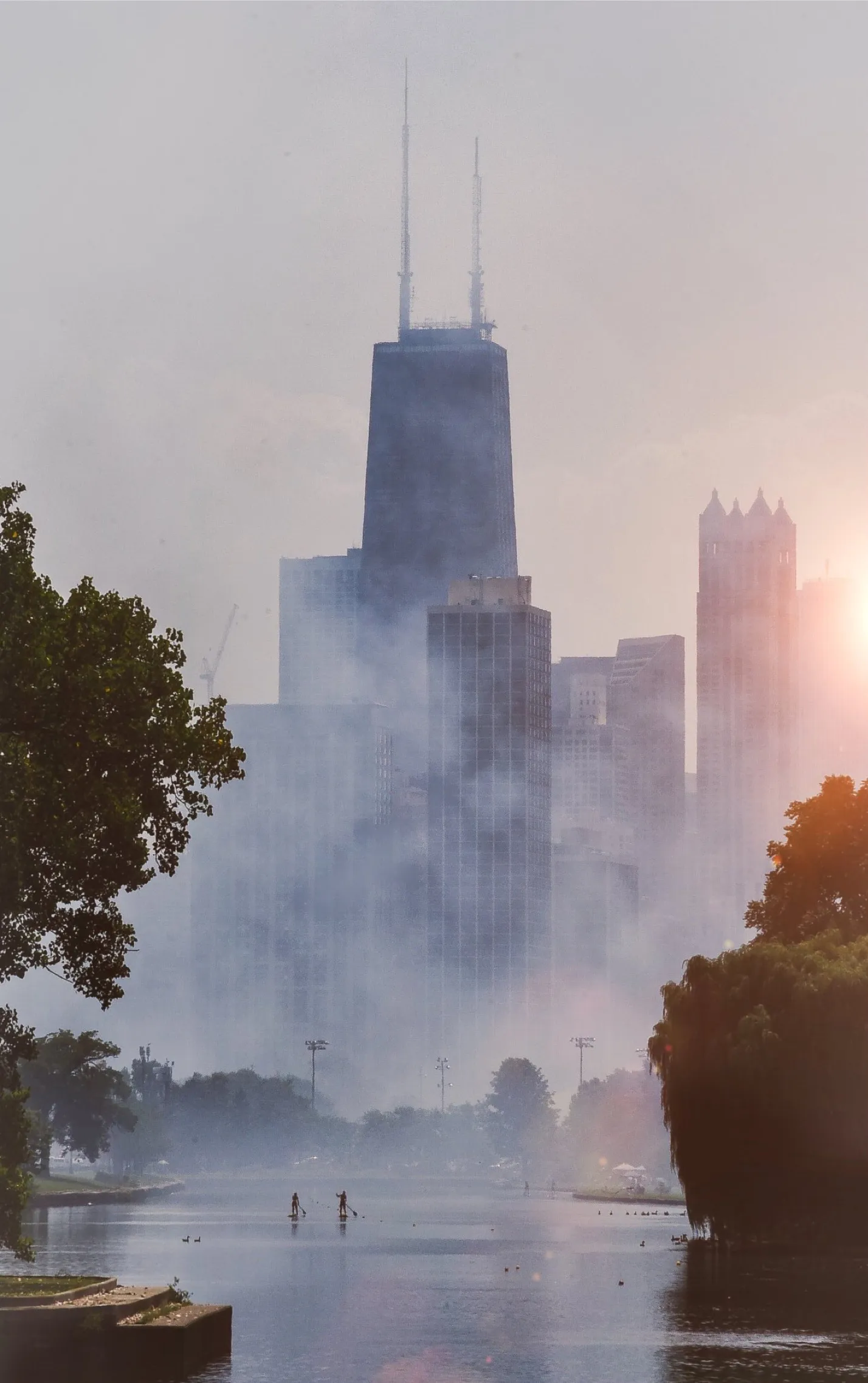 As a farewell to the City that built my career, I am auctioning my favorite piece from my 7 year run in this city. This photograph was taken in 2019 during the Chicago airshow. Like most mornings I woke up and headed straight out the door with my camera,  rolling the dice and hoping to capture something unique and beautiful. This day I was exceptionally lucky. The crowds from the Chicago airshow were packed onto Fullerton Beach, and I wanted to be there in hopes of a good photograph. Before I could get there I had to pass over the bridge on Fullerton Avenue, a view I had grown accustomed to. Today, however, things were different. Just as I crossed, two Aerobatic Aircraft swung over the beach, releasing smoke trails as they went. The noise was overpowering, but as I looked over my right shoulder I was suddenly plunged into silence. There, on the water, were two paddle boarders. I am not sure how long I stood there before I brought my view finder to my eye, but for those moments I looked over the skyline and how small these people looked emerging from the fog. I realized how incredible this city was because of how small we were in the greater story that continues to be written here since 1837. I felt the importance of understanding my unimportance, and that brought me an immense amount of peace. I know this city will live on in the pages of my writing and my artwork, but for this photograph. Just for a moment. It was Chicago's pages that I was writing in.