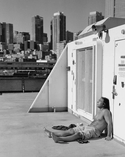 It's no secret that Seattle is a relatively gloomy place. The winters are cold, rainy, and the sun sets early. However, when summer finally arrives, Seattle truly comes alive. The days are long, and everyone gets outside to soak up as much sunlight as possible. 

On a recent ferry ride from Seattle to Bremerton, I came up the stairs to find this man sitting outside, shirt off, basking in the sun. Getting as close as I could, while being as quiet as possible, I snapped a few frames and got the composition I wanted. 

Please enjoy "Slumber on the Sound 2".