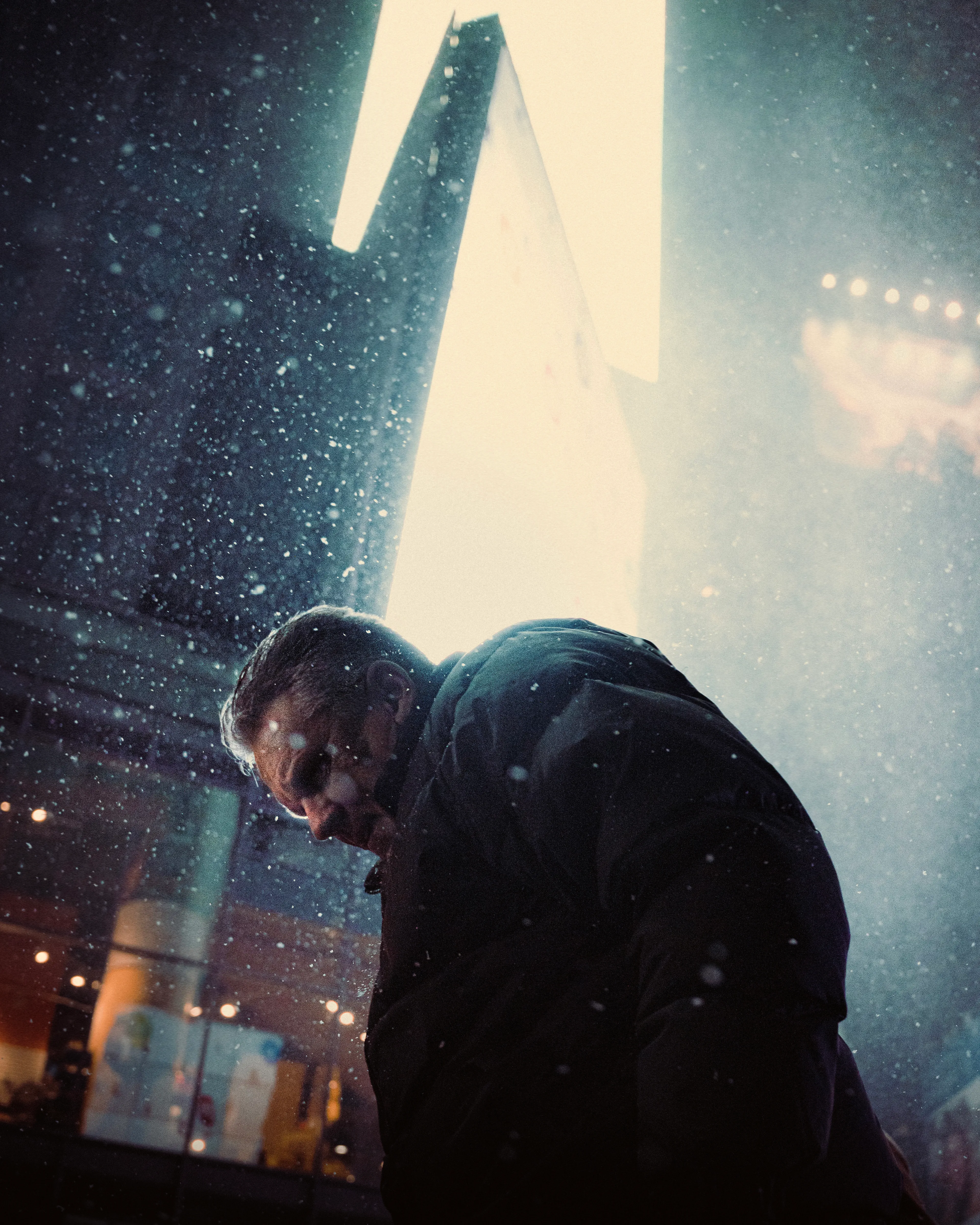 "Flurries" is a photograph captured in midtown New York City late night during a snowstorm in 2022. 

Scenes and situations with strong emotions are what I gravitate to when documenting the world and this picture has quite that feeling to it. With the city's signature digital billboards highlighting the tension in the subject's expression, you can almost see on his face everything he's going through at that moment as he makes his way unshielded through the storm.
