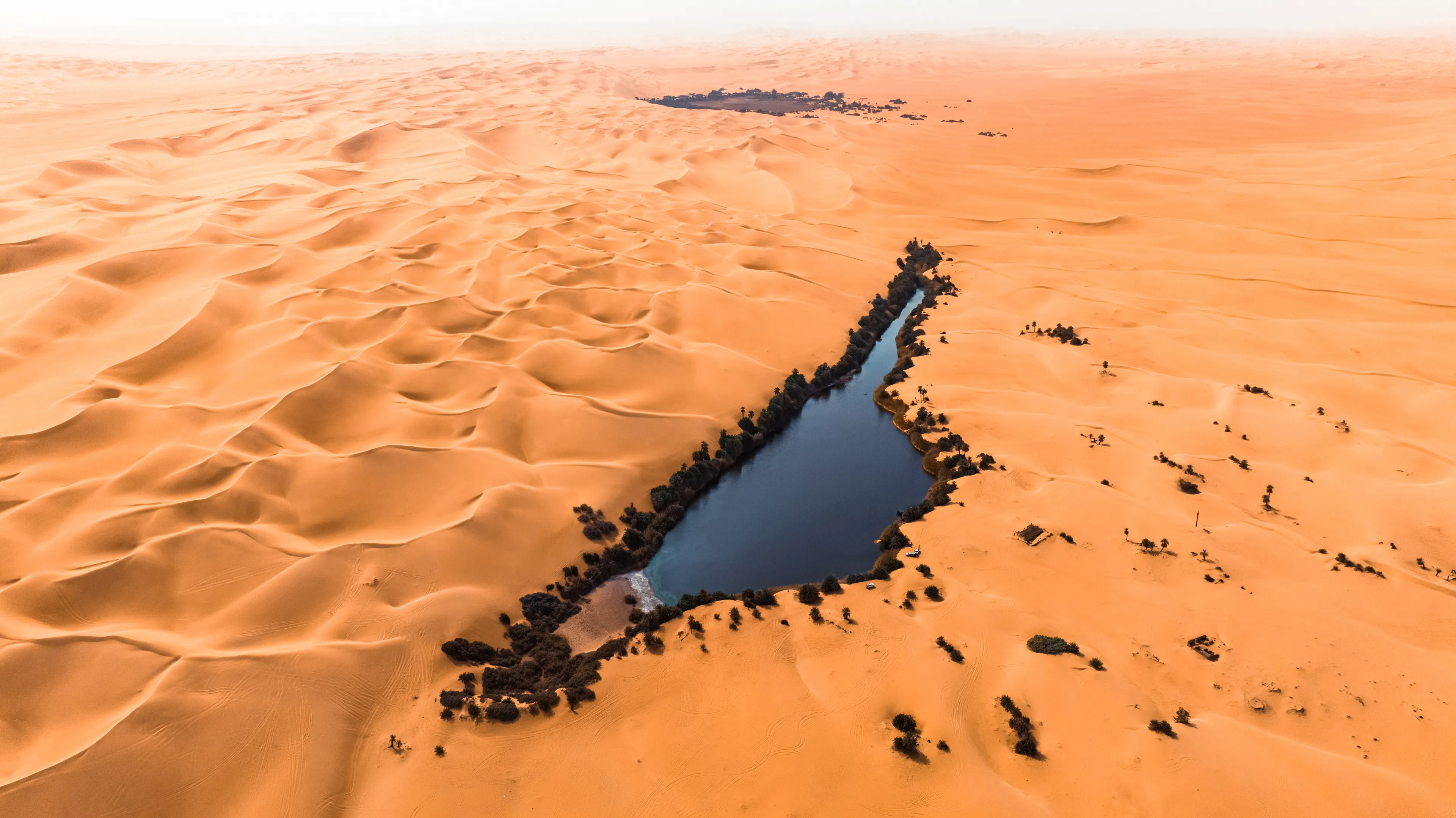 We knew where we were headed. The Ubari lakes region is a place full of history made of geological eras of an impactful force. Once a boundless body of water comparable in size to today's Czech Republic, this area is now a vast expanse of sand and towering dunes.

In linear formation with three vehicles we emerge from a valley and head towards the oasis of Umm Al Ma. A mystical and enchanted place in the middle of nowhere.

Umm al-Maa, meaning "Mother of Water," is recognized for its slender, elongated form, perhaps contributing to its distinction as the most aesthetically pleasing among the Ubari lakes.