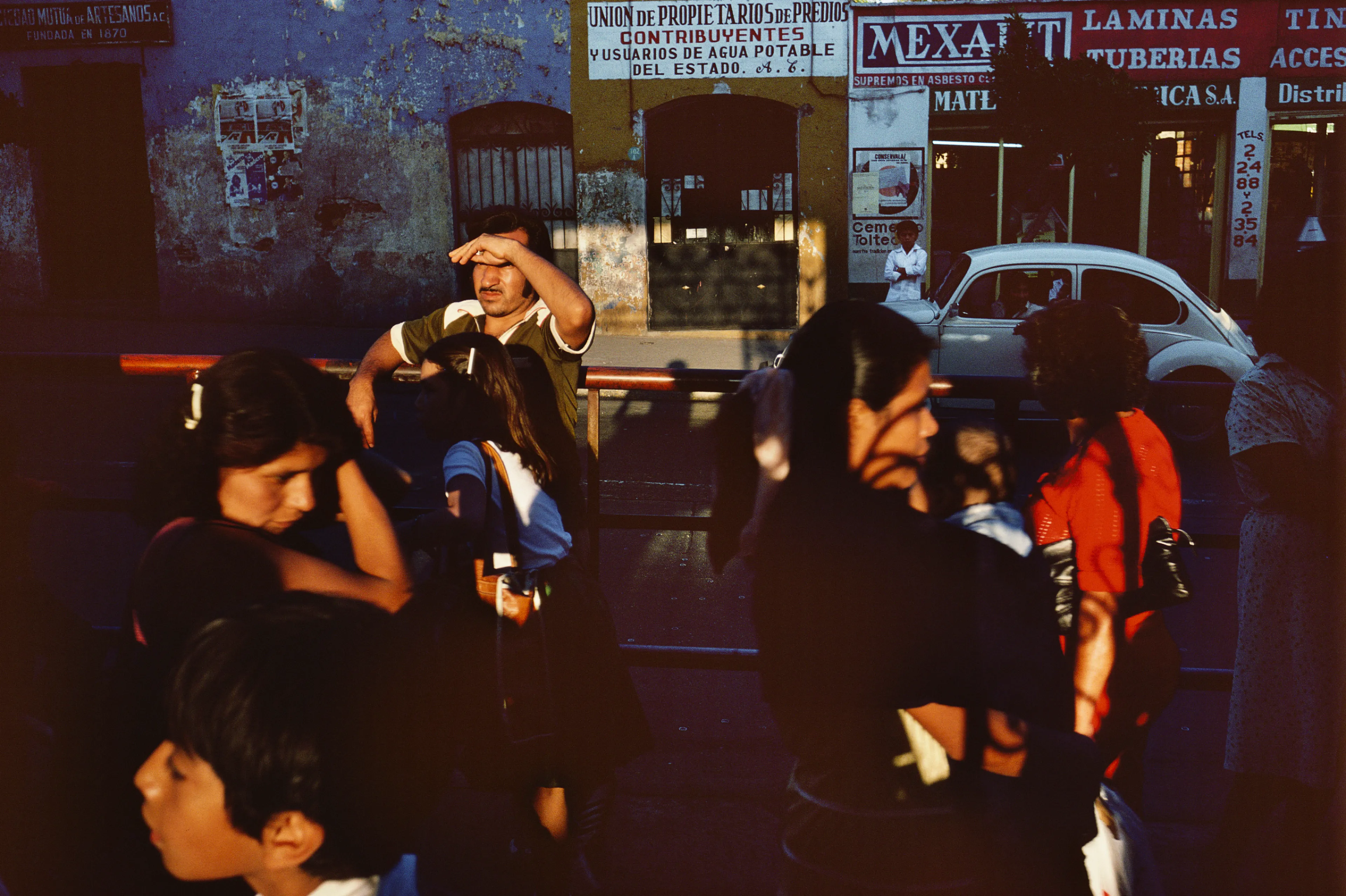 From his first visit in 1975, he was immediately captivated by the vibrant life in the streets of Mexico. While his early black and white photos often feature stark, striking graphics, his foray into color photography starting in 1978—inspired by the light and color of the Mexican streets—marks a turning point in his work.

Throughout his work from Mexico, his rich compositions create compelling visual complexity—‘La Calle’ features strong, saturated colors, which evoke haunting, enigmatic scenes of the everyday. “I work extremely intuitively. I wander, I respond,” he says. “Am I aware of certain elements rationally at times? Sure. But I think that often when I am more aware of them, it usually means that the picture falls flat.”

Webb somehow manages to capture these surprising scenes, which add an otherworldly poetry to the genre of street photography.