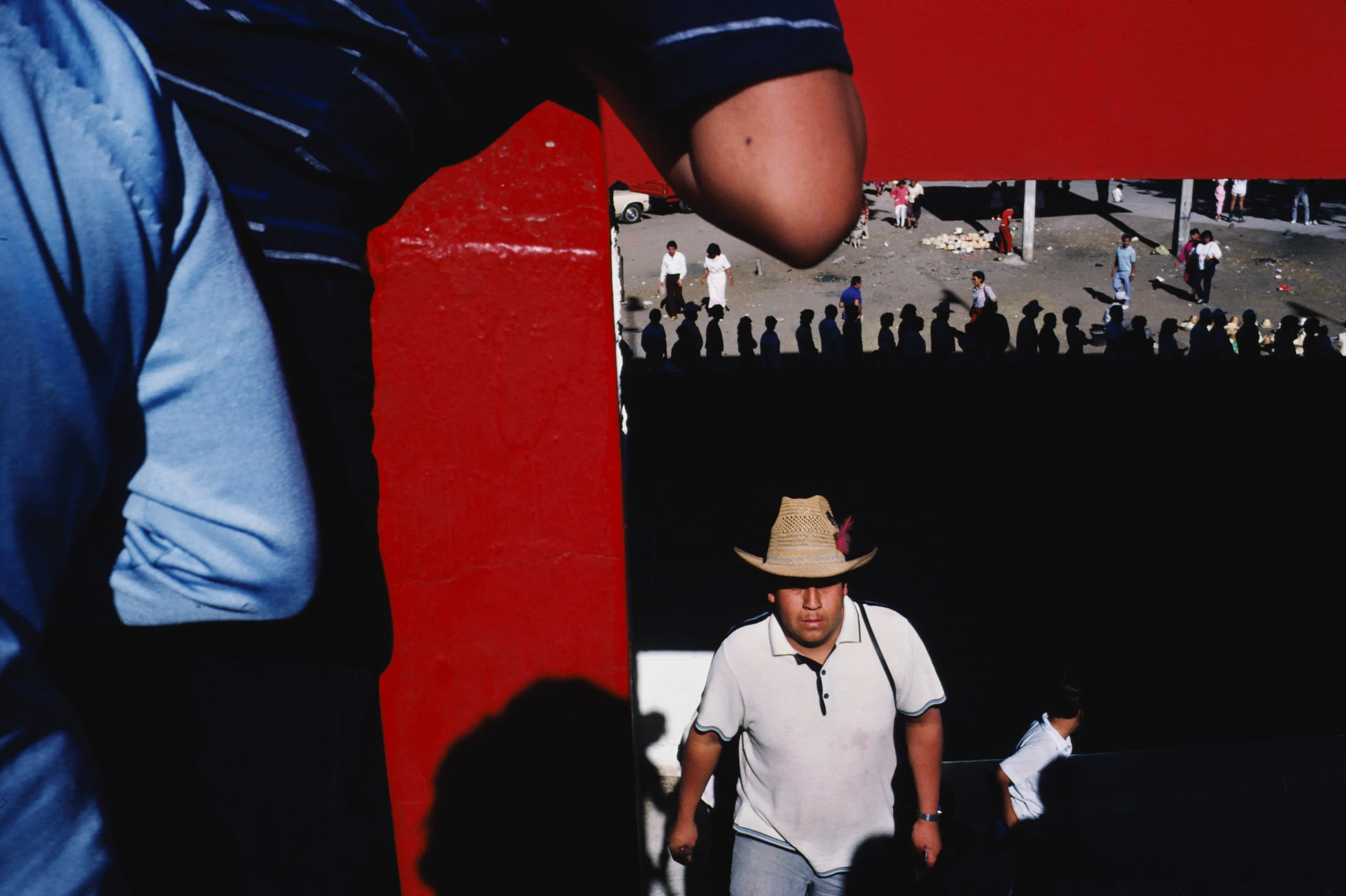 From his first visit in 1975, he was immediately captivated by the vibrant life in the streets of Mexico. While his early black and white photos often feature stark, striking graphics, his foray into color photography starting in 1978—inspired by the light and color of the Mexican streets—marks a turning point in his work.

Throughout his work from Mexico, his rich compositions create compelling visual complexity—‘La Calle’ features strong, saturated colors, which evoke haunting, enigmatic scenes of the everyday. “I work extremely intuitively. I wander, I respond,” he says. “Am I aware of certain elements rationally at times? Sure. But I think that often when I am more aware of them, it usually means that the picture falls flat.”

Webb somehow manages to capture these surprising scenes, which add an otherworldly poetry to the genre of street photography.