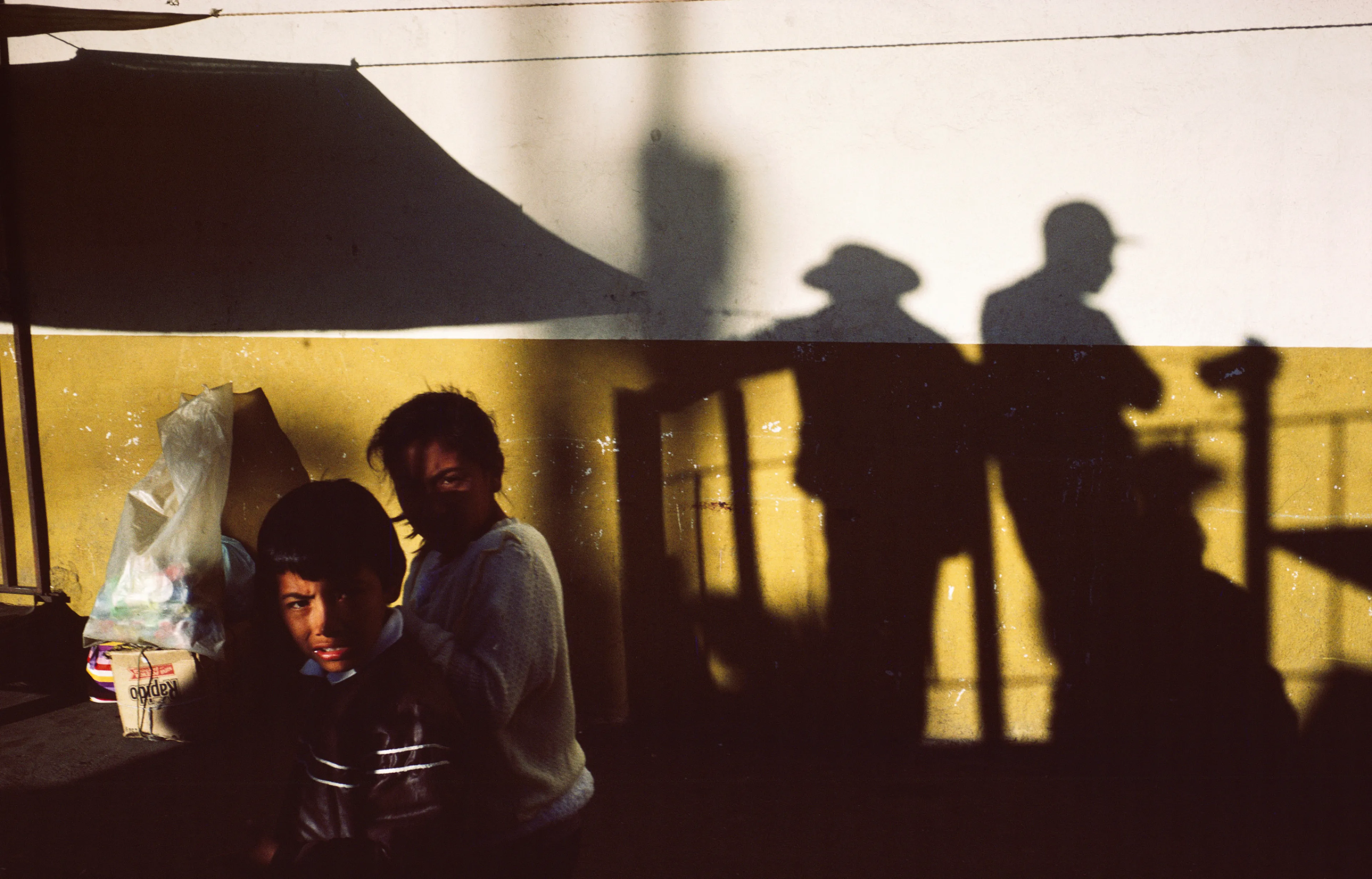 From his first visit in 1975, he was immediately captivated by the vibrant life in the streets of Mexico. While his early black and white photos often feature stark, striking graphics, his foray into color photography starting in 1978—inspired by the light and color of the Mexican streets—marks a turning point in his work.

Throughout his work from Mexico, his rich compositions create compelling visual complexity—‘La Calle’ features strong, saturated colors, which evoke haunting, enigmatic scenes of the everyday. “I work extremely intuitively. I wander, I respond,” he says. “Am I aware of certain elements rationally at times? Sure. But I think that often when I am more aware of them, it usually means that the picture falls flat.”

Webb somehow manages to capture these surprising scenes, which add an otherworldly poetry to the genre of street photography.
