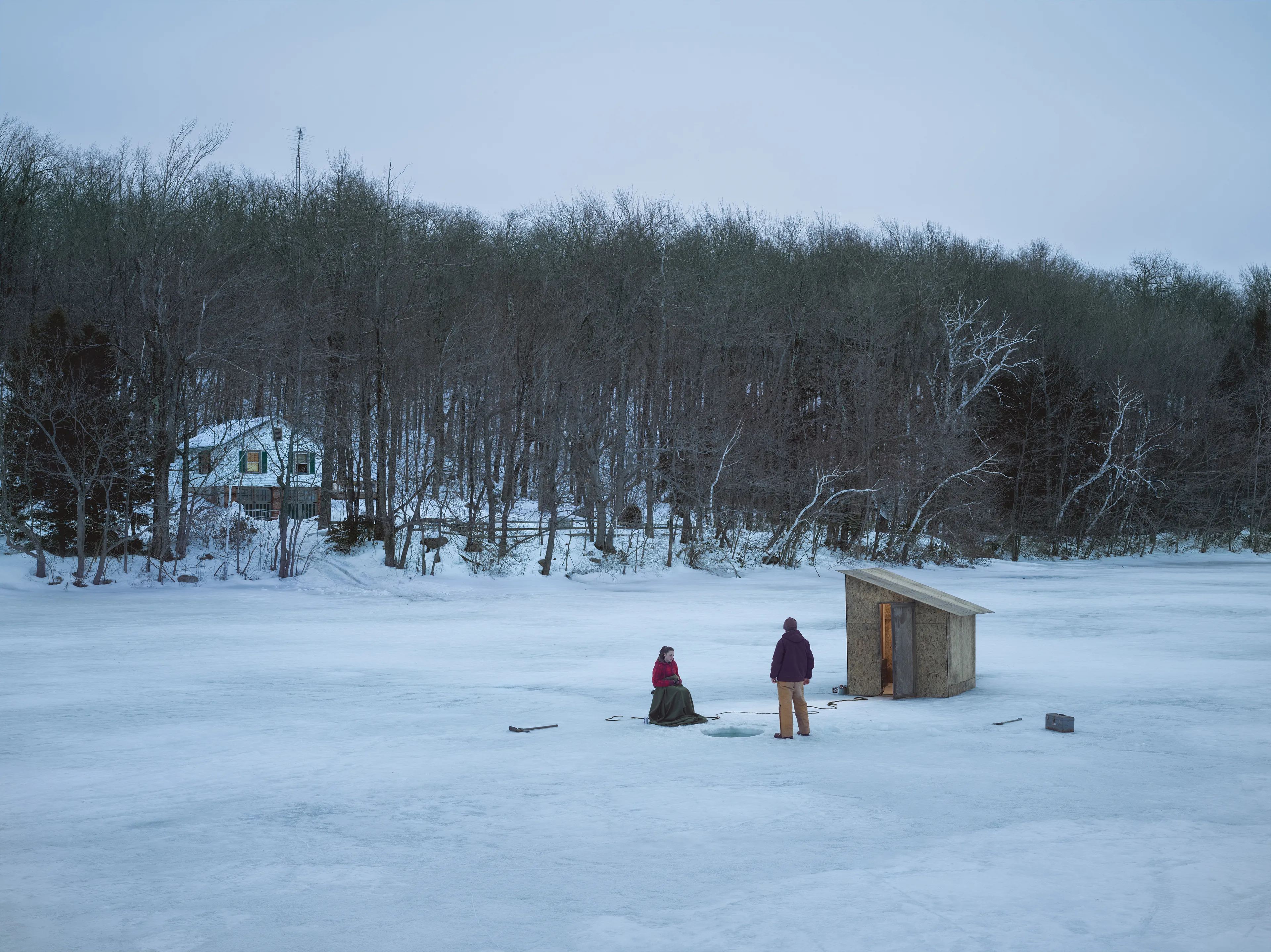 Cathedral of the Pines (2013-14) was produced in the rural woodlands surrounding Becket, Massachusetts, a small town that was first settled in 1740 and home to the titular forest trail the work is named after. There’s a pervasive stillness that exists in the works of this collection. As we viewers tour these pictures, we find the quietude of the cabins and forest landscapes become hosts to a dark and meditative dwelling of the subjects that populate these places. As with much of Crewdson’s work, the loneliness and alienation of his subjects are deeply pronounced, and the cool blue and green hues that saturate the frames characterize the emotional content to pair with the unusual encounters received by their viewers.

While the domestic interior scenes extend a trademark narrative form that the photographer is widely recognized for, Crewdson’s landscape scenes enrichen the series by taking inspiration from 19th century American landscape painting. The compositional exactitudes and ornate geometries the photographer employs contextualize his images in the framework of classical tradition. Cathedral of the Pines thus becomes an update to the legacy of ‘Americana’, and a revisionist practice which sees the lores of American ideals become overtaken with the internal disturbances of its unwell occupants.

Edition: 1 of 1