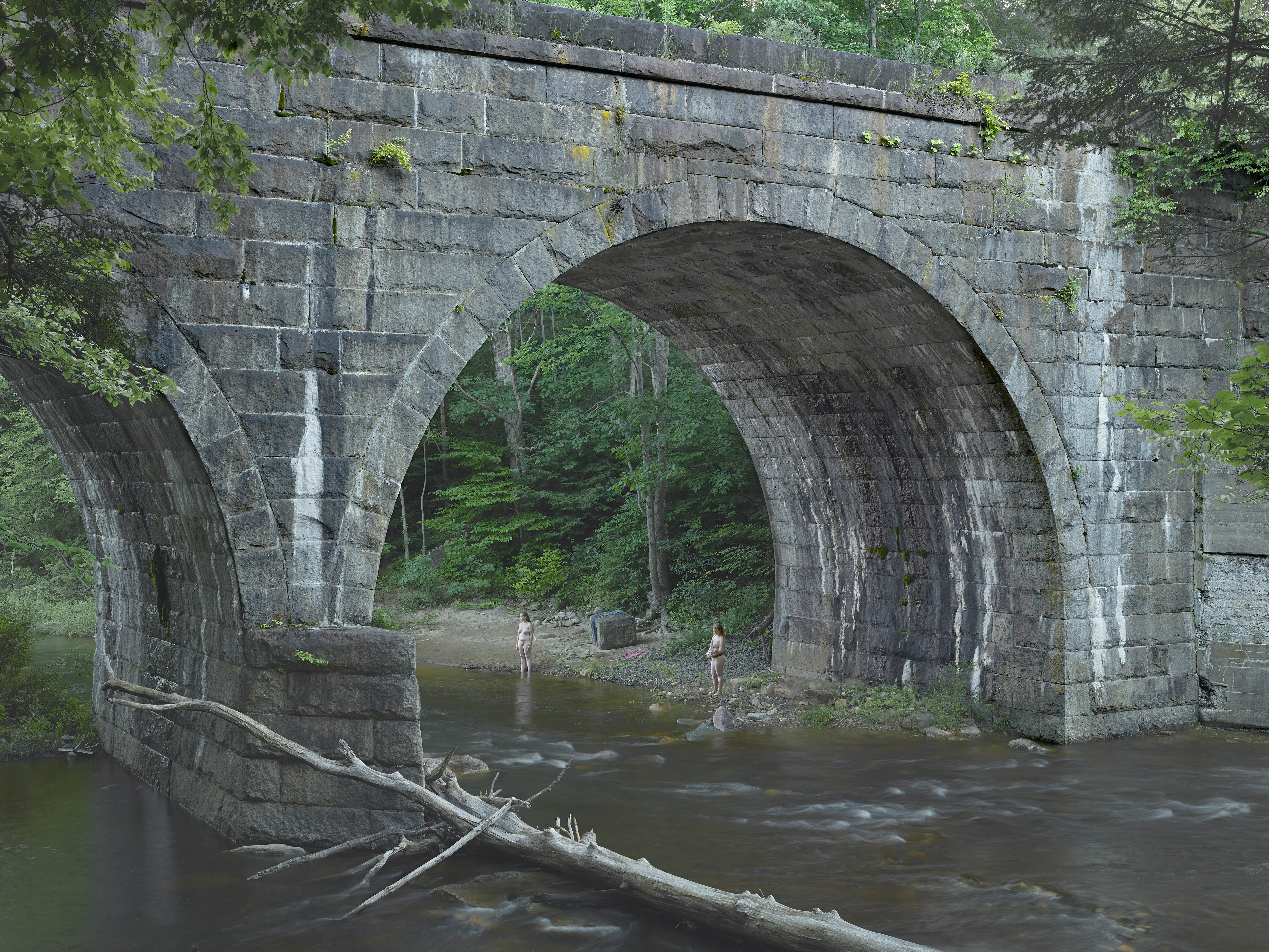 Cathedral of the Pines (2013-14) was produced in the rural woodlands surrounding Becket, Massachusetts, a small town that was first settled in 1740 and home to the titular forest trail the work is named after. There’s a pervasive stillness that exists in the works of this collection. As we viewers tour these pictures, we find the quietude of the cabins and forest landscapes become hosts to a dark and meditative dwelling of the subjects that populate these places. As with much of Crewdson’s work, the loneliness and alienation of his subjects are deeply pronounced, and the cool blue and green hues that saturate the frames characterize the emotional content to pair with the unusual encounters received by their viewers.

While the domestic interior scenes extend a trademark narrative form that the photographer is widely recognized for, Crewdson’s landscape scenes enrichen the series by taking inspiration from 19th century American landscape painting. The compositional exactitudes and ornate geometries the photographer employs contextualize his images in the framework of classical tradition. Cathedral of the Pines thus becomes an update to the legacy of ‘Americana’, and a revisionist practice which sees the lores of American ideals become overtaken with the internal disturbances of its unwell occupants.

Edition: 1 of 1