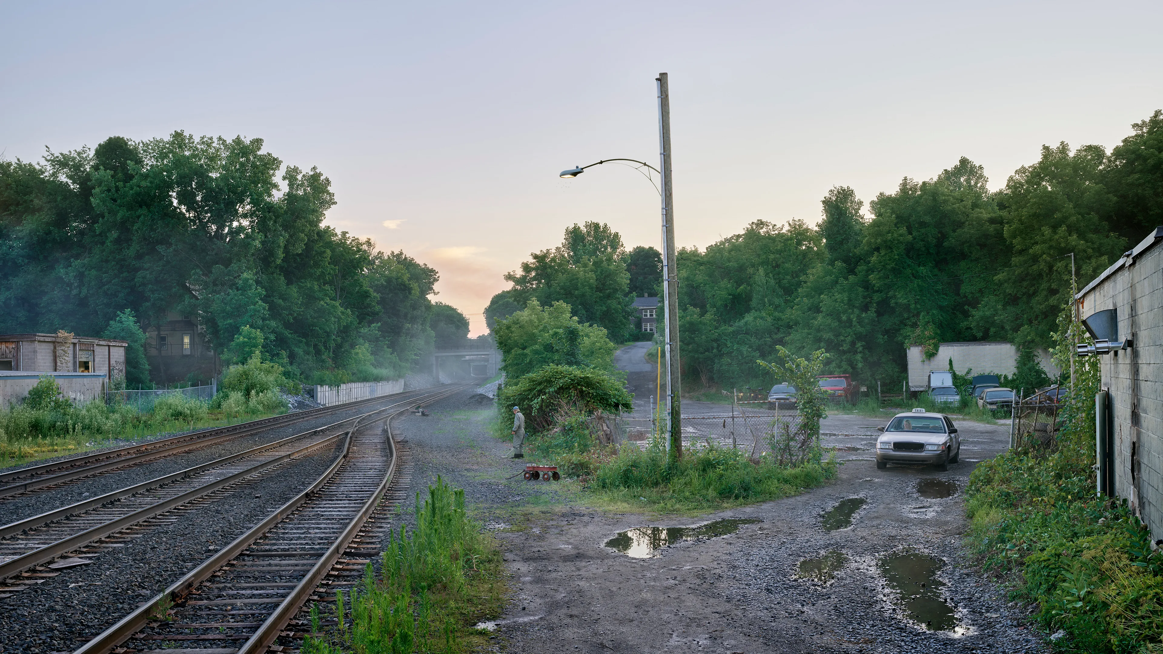 Within the frames of Crewdson’s body of work, An Eclipse of Moths (2018-19), we encounter the artist’s fascination with the idea of a haunted American landscape. Set in post-industrial small-town America, An Eclipse of Moths tours viewers through the quiet wreckage of rusted and downtrodden working-class environments. More than his previous work, feelings of emptiness pervade these pictures as the visual space depicts broad expanses of asphalt and concrete that appear neglected and forgotten. While Crewdson often uses human gesture to convey the deep-rooted anxieties that appear throughout his oeuvre, here the landscapes themselves become the subjects while their occupants perform as part of the environment, succumbing to it, and becoming defined by it. As with all Crewdson’s work, we experience encounters with secrets that we aren’t allowed to know. The artist provides us surfaces that are charged with dark emotional energy, and it is up to us as viewers to speculate on what resides behind it all while answers remain just slightly beyond our grasp.

Edition: 1 of 1