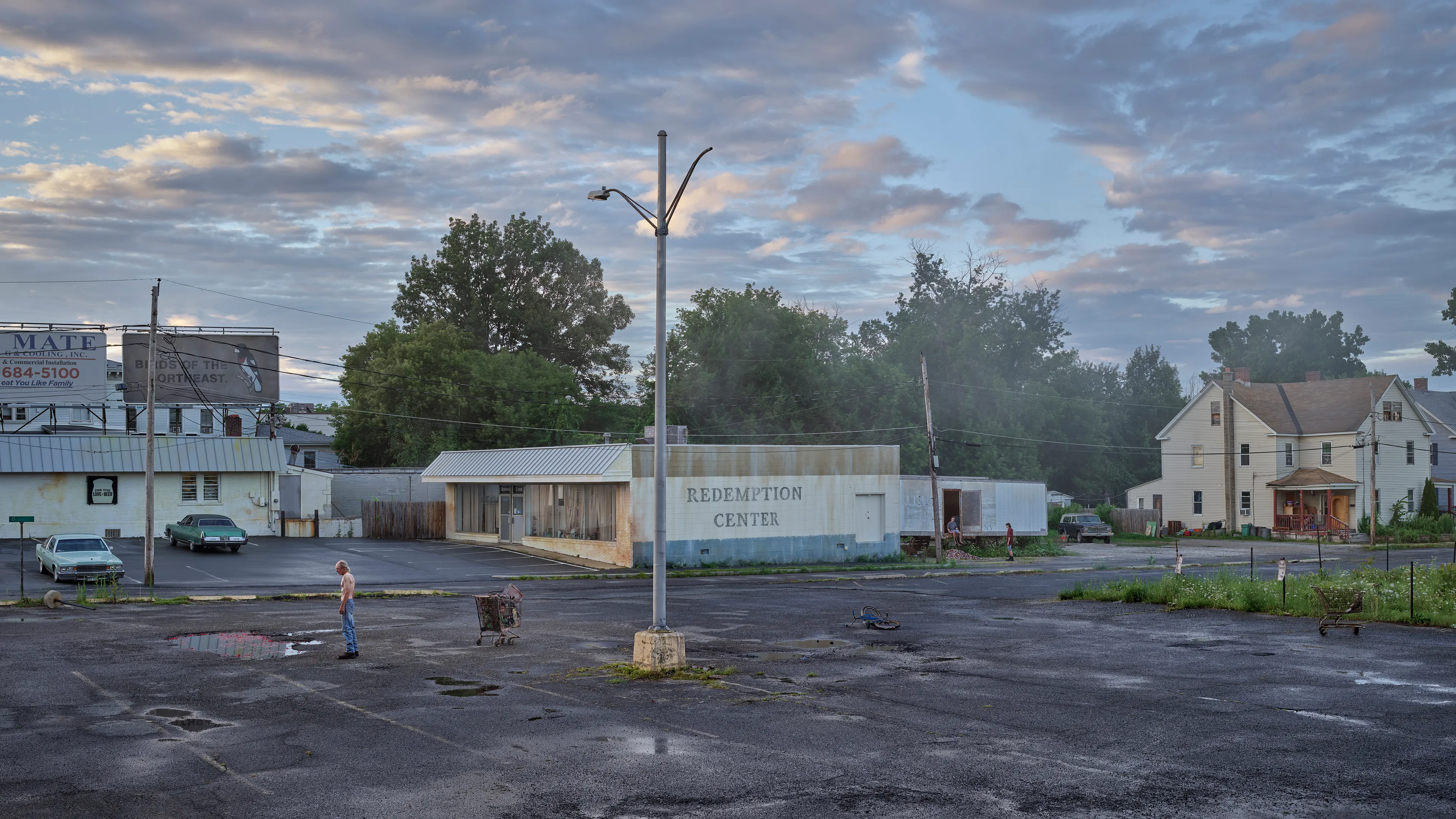 Within the frames of Crewdson’s body of work, An Eclipse of Moths (2018-19), we encounter the artist’s fascination with the idea of a haunted American landscape. Set in post-industrial small-town America, An Eclipse of Moths tours viewers through the quiet wreckage of rusted and downtrodden working-class environments. More than his previous work, feelings of emptiness pervade these pictures as the visual space depicts broad expanses of asphalt and concrete that appear neglected and forgotten. While Crewdson often uses human gesture to convey the deep-rooted anxieties that appear throughout his oeuvre, here the landscapes themselves become the subjects while their occupants perform as part of the environment, succumbing to it, and becoming defined by it. As with all Crewdson’s work, we experience encounters with secrets that we aren’t allowed to know. The artist provides us surfaces that are charged with dark emotional energy, and it is up to us as viewers to speculate on what resides behind it all while answers remain just slightly beyond our grasp.

Edition: 1 of 1