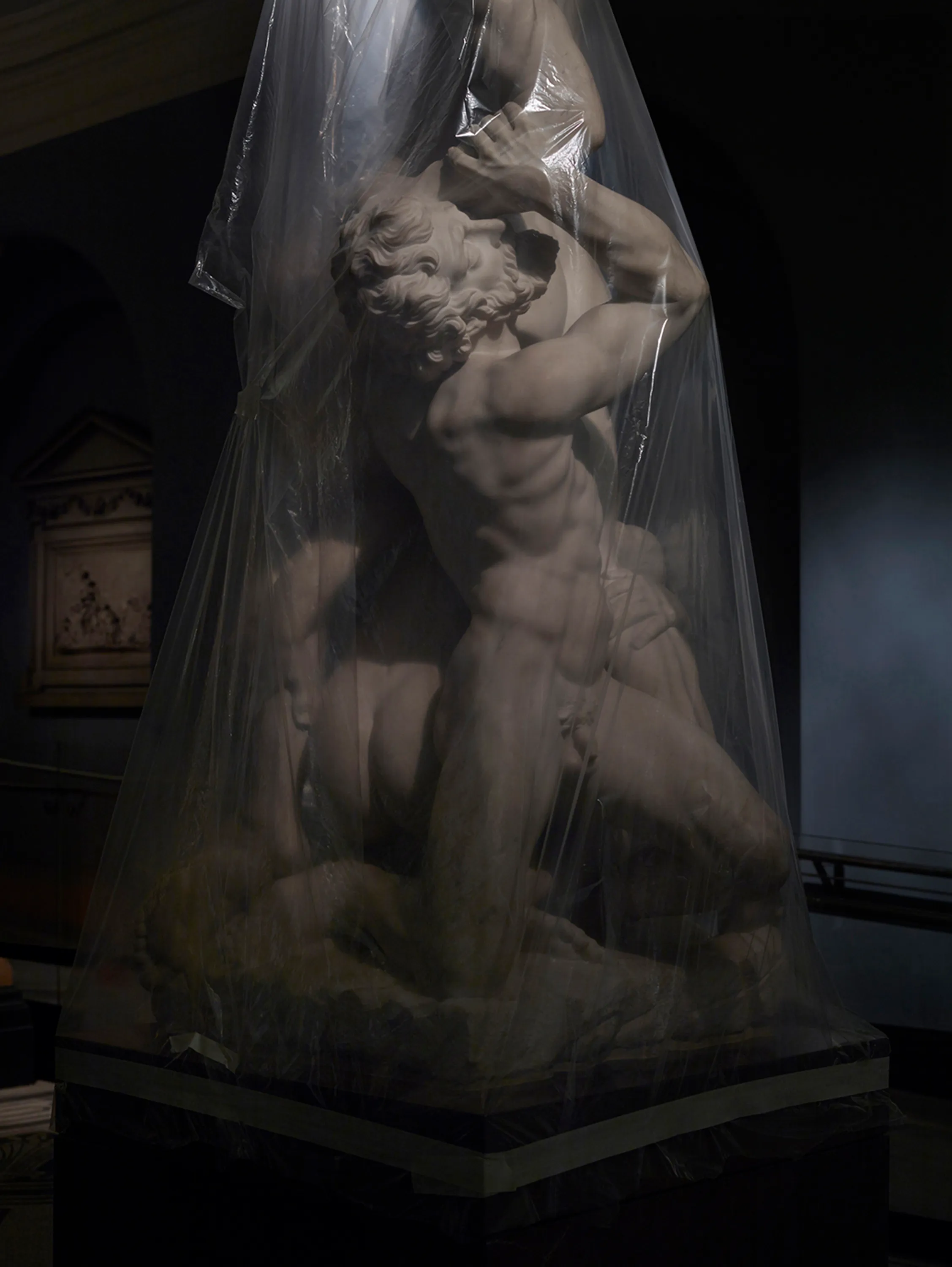 Assembly presents “Shrouded Sculptures” by UK based visual artist Simon Roberts. This NFT collection is a selection of photographs taken during the second Covid-19 lockdown whilst London’s Victoria and Albert Museum was closed to the public. These veiled statues, located in the Museum’s Dorothy and Michael Hintze Galleries, were covered for their protection during refurbishment and Roberts envisions them as a metaphor for our wider experience of the Covid-19 pandemic. The images speak of the extraordinary events of the past year, a global population suspended in time, restricted of movement and freedoms. We were forced to separate from one another, or if we were to meet, we were to hug through thick plastic sheeting, or wave through windows. The beauty of our world felt elusive, hidden beneath an entanglement of political mixed messages and misleading rhetoric. Unlike the statues of merchants, statesmen and traders, many of the sculptures in this gallery represent mythological or allegorical subjects. We see ancient mythology and 18th century neo-classicism meet 21st century plastic and gaffa tape, and the juxtaposition is eerie, disorientating and beautiful.

Simon Roberts is a visual artist based in the UK. Widely recognised for his large-format, tableaux photographs of the British landscape, his practice also encompasses video, text and installation work, which together, interrogate notions of identity and belonging, and the complex relationship between history, place and culture. His work has been exhibited nationally and internationally, and resides in major public and private collections, including the George Eastman House, Deutsche Börse Art Collection and Victoria & Albert Museum.