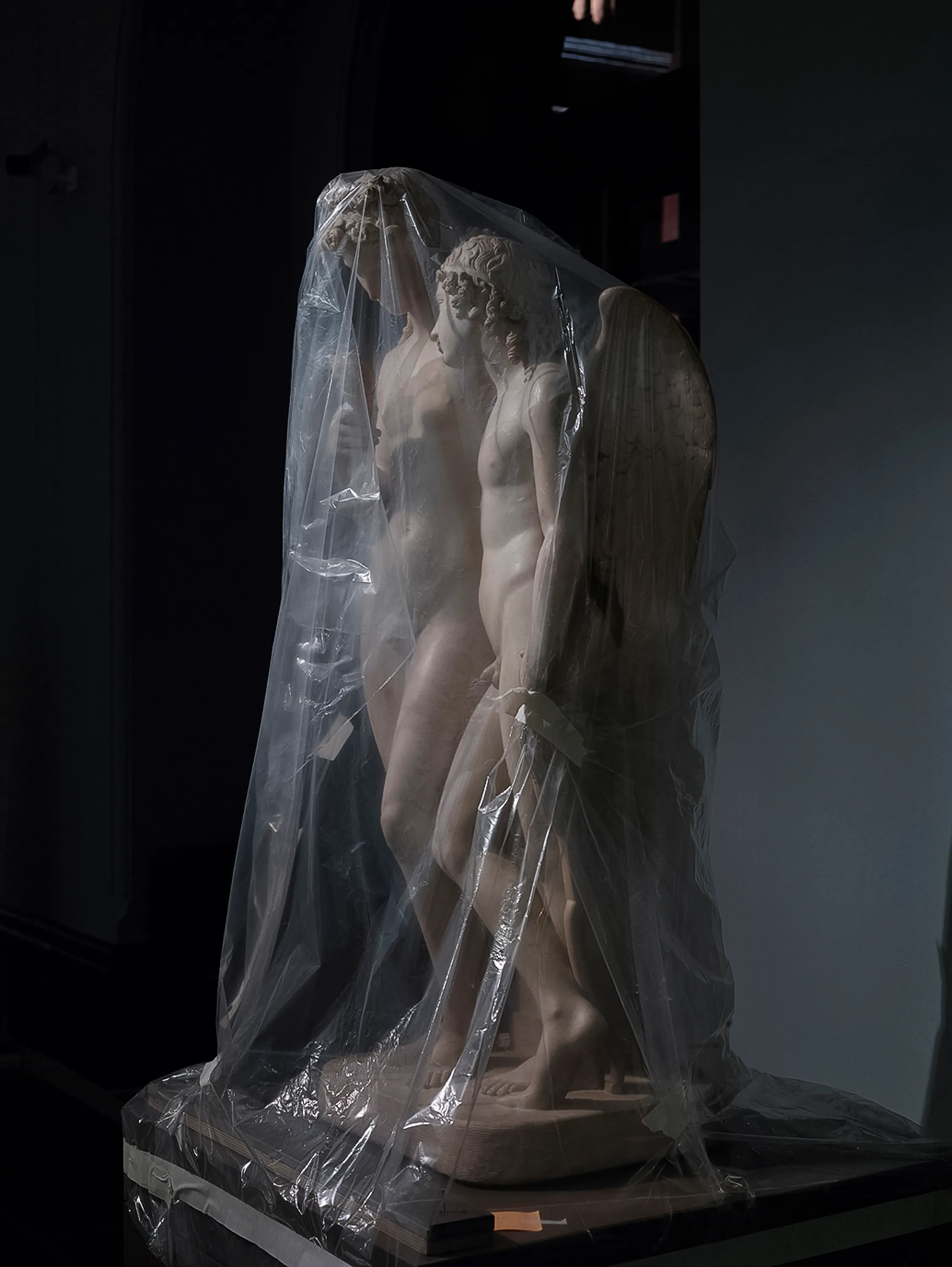 Assembly presents “Shrouded Sculptures” by UK based visual artist Simon Roberts. This NFT collection is a selection of photographs taken during the second Covid-19 lockdown whilst London’s Victoria and Albert Museum was closed to the public. These veiled statues, located in the Museum’s Dorothy and Michael Hintze Galleries, were covered for their protection during refurbishment and Roberts envisions them as a metaphor for our wider experience of the Covid-19 pandemic. The images speak of the extraordinary events of the past year, a global population suspended in time, restricted of movement and freedoms. We were forced to separate from one another, or if we were to meet, we were to hug through thick plastic sheeting, or wave through windows. The beauty of our world felt elusive, hidden beneath an entanglement of political mixed messages and misleading rhetoric. Unlike the statues of merchants, statesmen and traders, many of the sculptures in this gallery represent mythological or allegorical subjects. We see ancient mythology and 18th century neo-classicism meet 21st century plastic and gaffa tape, and the juxtaposition is eerie, disorientating and beautiful.

Simon Roberts is a visual artist based in the UK. Widely recognised for his large-format, tableaux photographs of the British landscape, his practice also encompasses video, text and installation work, which together, interrogate notions of identity and belonging, and the complex relationship between history, place and culture. His work has been exhibited nationally and internationally, and resides in major public and private collections, including the George Eastman House, Deutsche Börse Art Collection and Victoria & Albert Museum.