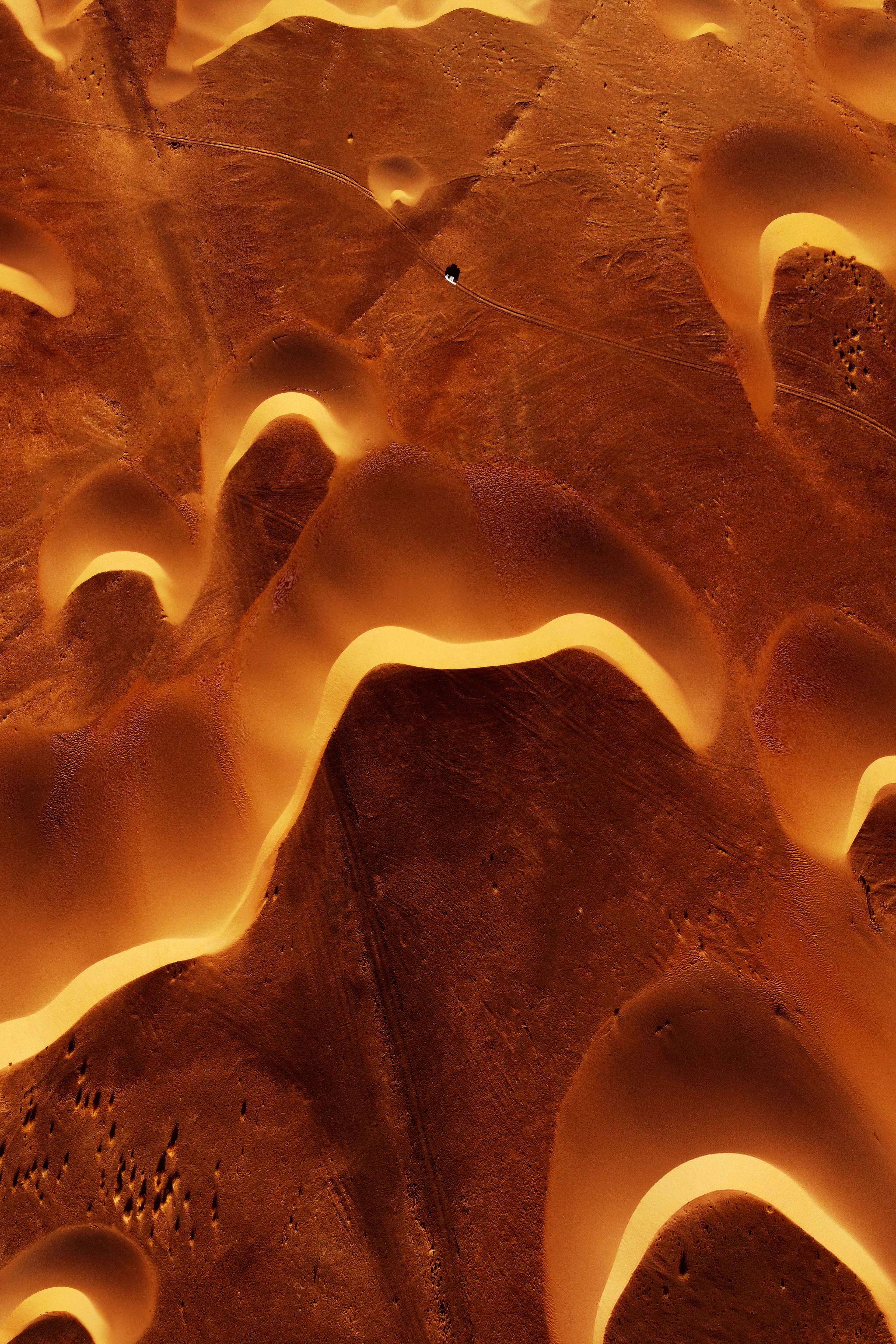 "Melting Dunes" was shot in a remote area of ​​the Sahara in Mauritania during one of my recent expeditions. It contrasts the grandeur of the desert and dunes against the smallness of human beings. A top-down aerial perspective taken at 400 meters of relative altitude, the shot transports us into a scene of surreal proportions. The car crosses the desert as the dunes appear to almost be melting around it.