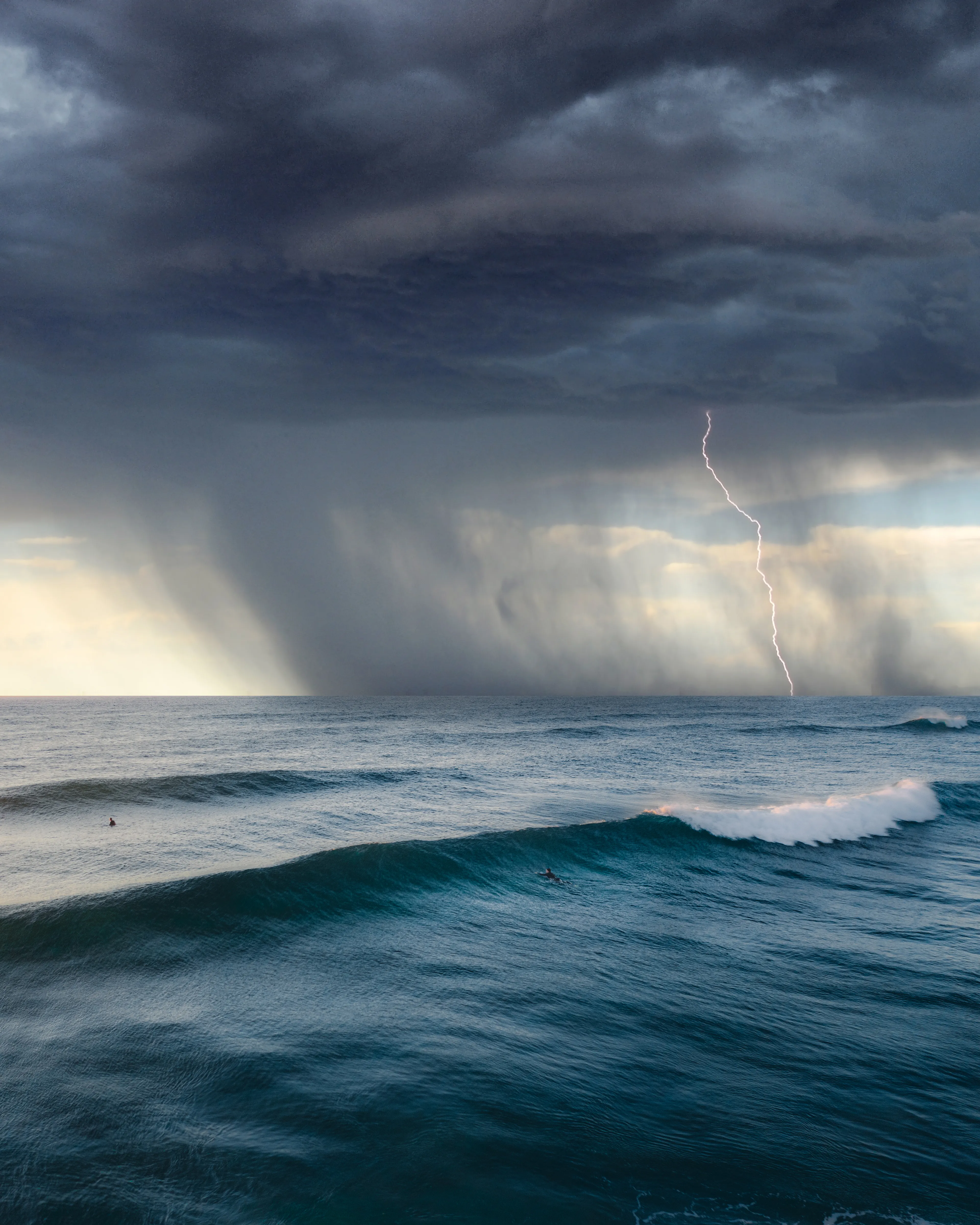 Grail shot. Capturing lightning over the ocean is rare enough for me, let alone composed on a sunny afternoon with surfers in frame while a big storm front rolls in from the south. 

This is now the benchmark for this series and I wont stop chasing ocean storms until I can match it or beat it and will still probably never be satisfied. The thrill of the chase is so addictive. Throw in the danger of losing your drone way out to sea as you face 50-60 kilometres per hour winds and I challenge anyone to stop getting after images like this again and again and again. Pulling off a series of images like this has proven the most challenging subject for my photography, including finding whales and marine life.

This image represents a very powerful memory for me and my surfing journey. The experience of being out to sea catching waves and being caught in a huge storm that lasted only minutes, but was enough to shake me to my core. I look forward to sharing this story with the owner of this NFT.

Artist: New Light Visuals

Title: Event Horizon

Edition: 1/1

License: Extended Editorial