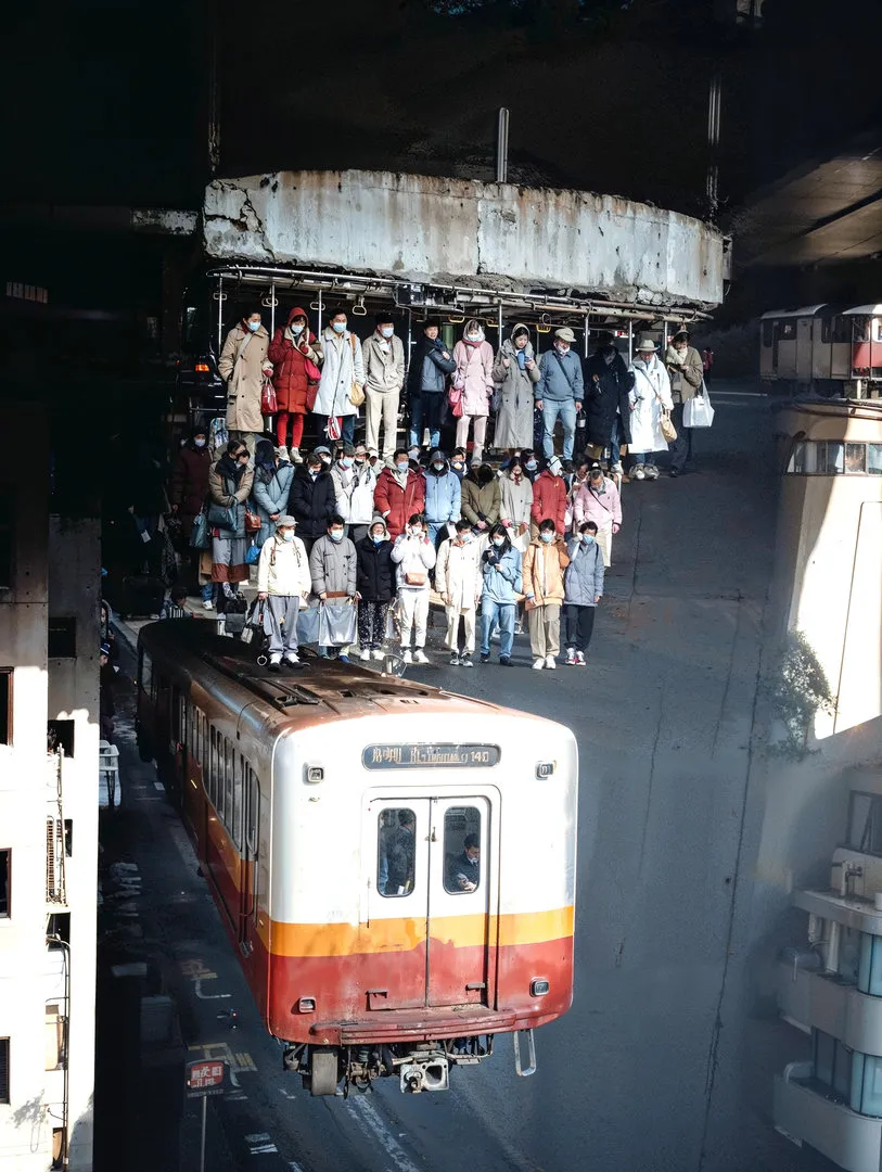 Commuters dangle from the tracks, order inverted and precarious.