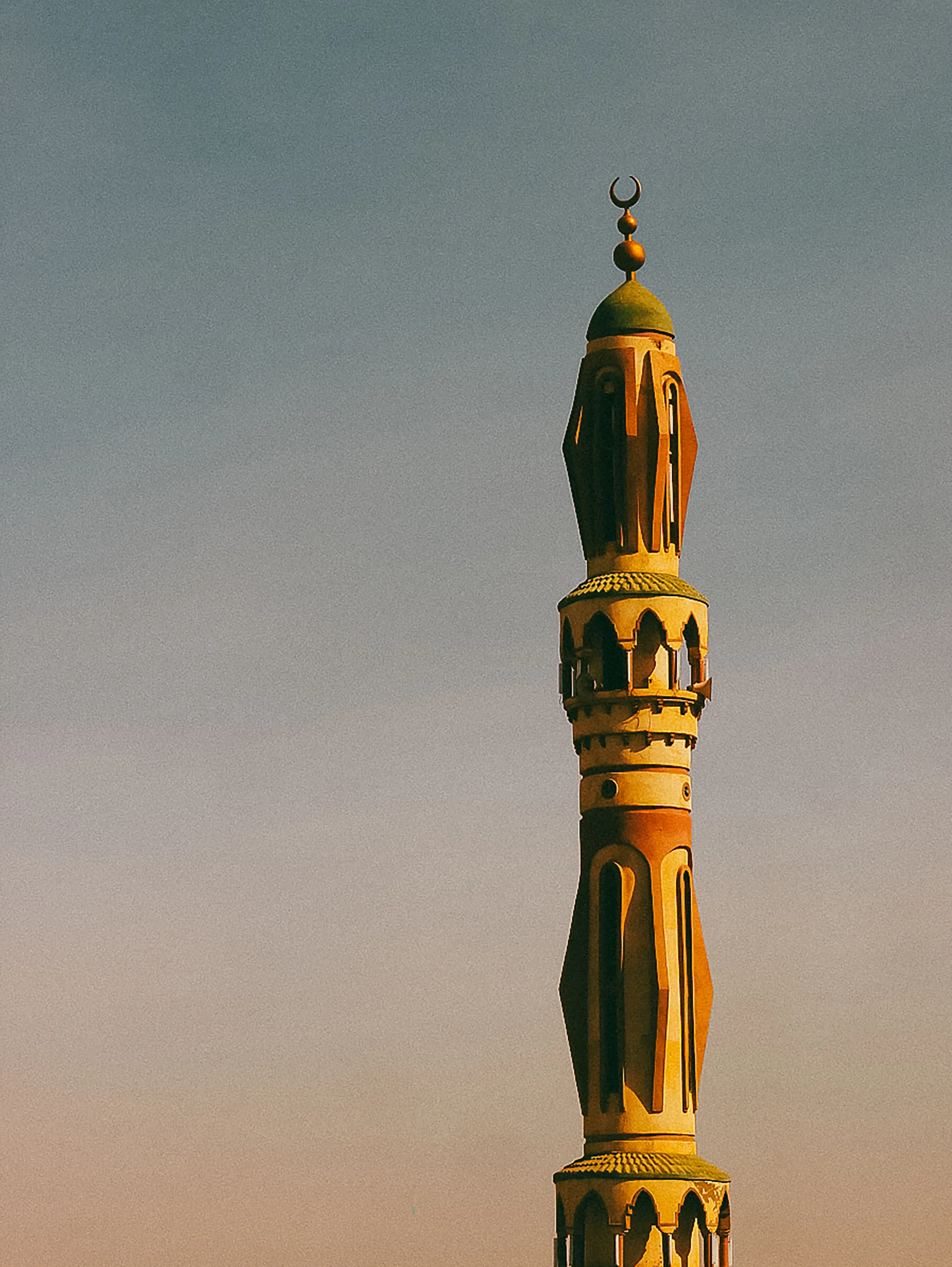 Taken from the rooftop of a relatives home in Al Ma'moora, this photograph captures a tall and colourful minaret during sunset.