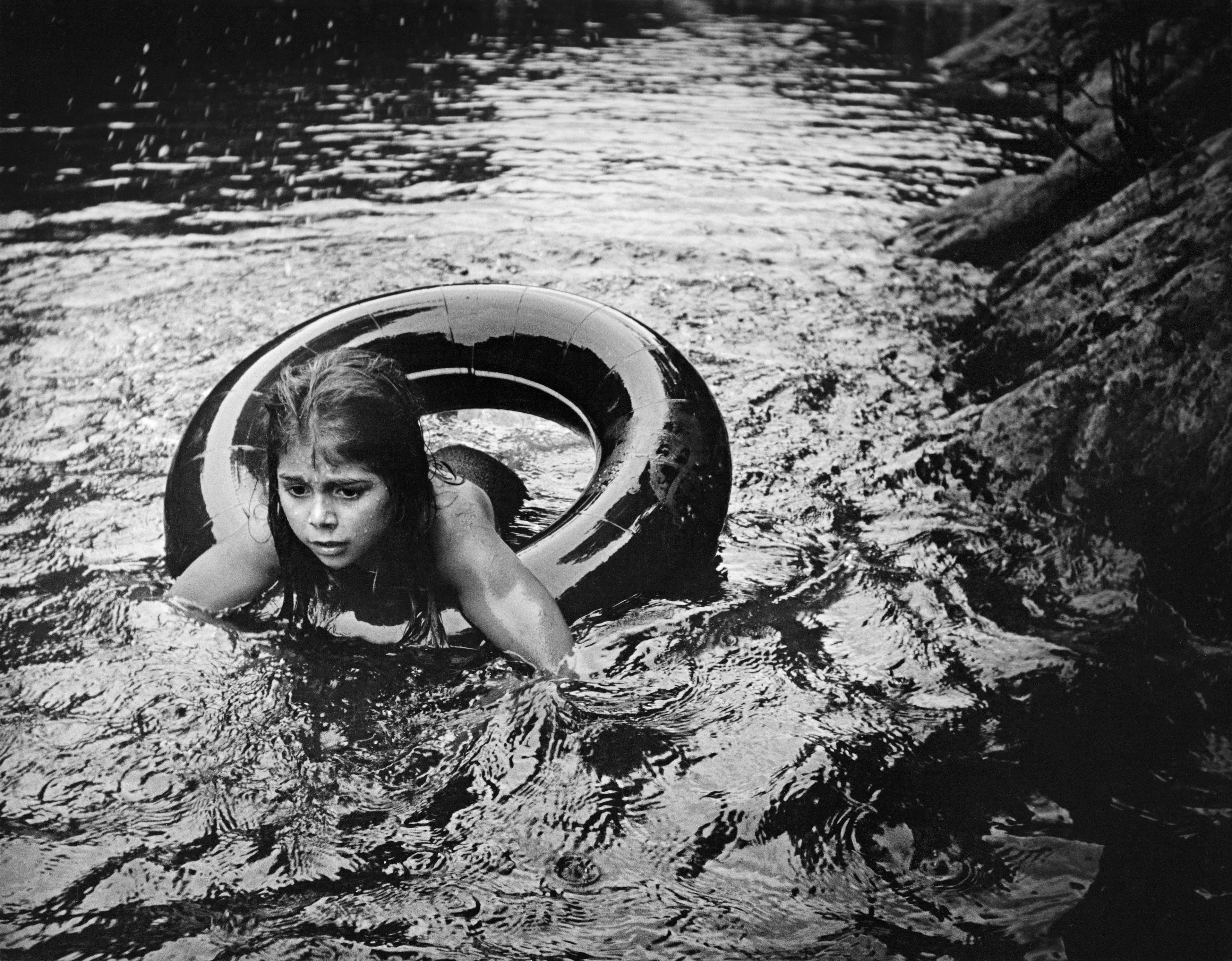 Magnum 75 #149 by W. Eugene Smith. Silver Lake, USA. 1958  
Juanita Floating in Inner Tube.

Magnum 75 is the inaugural NFT collection by Magnum Photos. Created in 2022 for the agency’s 75th anniversary year and released in three curations, the collection brings together 225 iconic images from Magnum photographers, taken across seven decades.

Each curation is composed in dialogue with a leading picture editor from across the globe and selected to embody the agency’s past, present, and future. This second curation was made in dialogue with Azu Nwagbogu, founder and director of African Artists’ Foundation and director of LagosPhoto Festival.

Nwagbogu says: “The vast Magnum archive reveals so much about the history of the modern world and its unresolved global issues with regard to ecology, humanity and technology. Rather than exploring Henri Cartier-Bresson’s ‘decisive moment,’ this collection studies the ‘indecisive moment’ — the interstitial spaces, the energized subjects floating in-between events, where little obvious action occurs but where the subject(s) seem to be caught in anticipation. Each image is charged with feeling, intent, foreboding, and meaning, composed with a sense of expectation that offers multiple scenarios and possibilities about past events. It is not revisionist history, but rather invites the collector and viewers to perhaps look at the image again, more closely.”

Edition: 1 of 1

© W. Eugene Smith/Magnum Photos 2022 All Rights Reserved  
www.magnumphotos.com/terms-conditions/