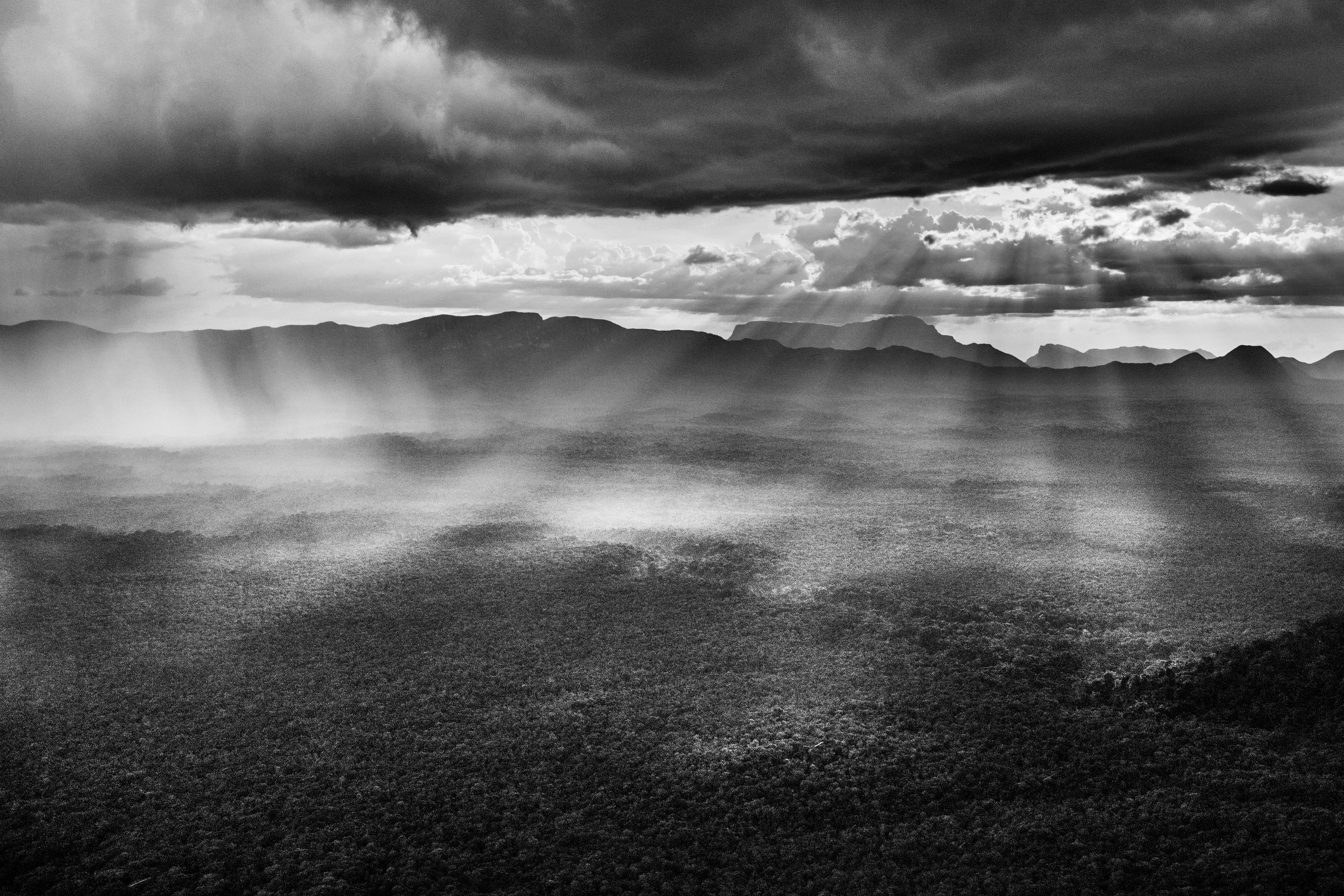 São Gabriel da Cachoeira Municipality, State of Amazonas, Brazil, 2018

Over the Amazon rainforest, rare is the day when you can see a clear sheet of blue sky or a solid blanket of gray cloud. Rather cloud formations offer an ever-changing spectacle. This begins in the morning when warm moist air rises from the jungle and makes contact with minuscule particles which permit the vapor to condense into water droplets and become little clouds resembling cotton balls known locally as aru. As the day advances, they rise and join forces and, temperature and wind speed permitting, gather strength to become a storm cloud known as a cumulonimbus. This is quite the most dangerous meteorological formation, reaching several thousand meters into the sky, spewing out pieces of ice and winds of up to 200 kilometers per hour (125 miles per hour) at the same time as sending lightning, strong winds, and fierce precipitation toward the jungle. Such is its force that even large aircraft will do everything to avoid it, helicopters immediately look for a jungle clearing in order to land and riverboats hurriedly take shelter from the blinding rain.