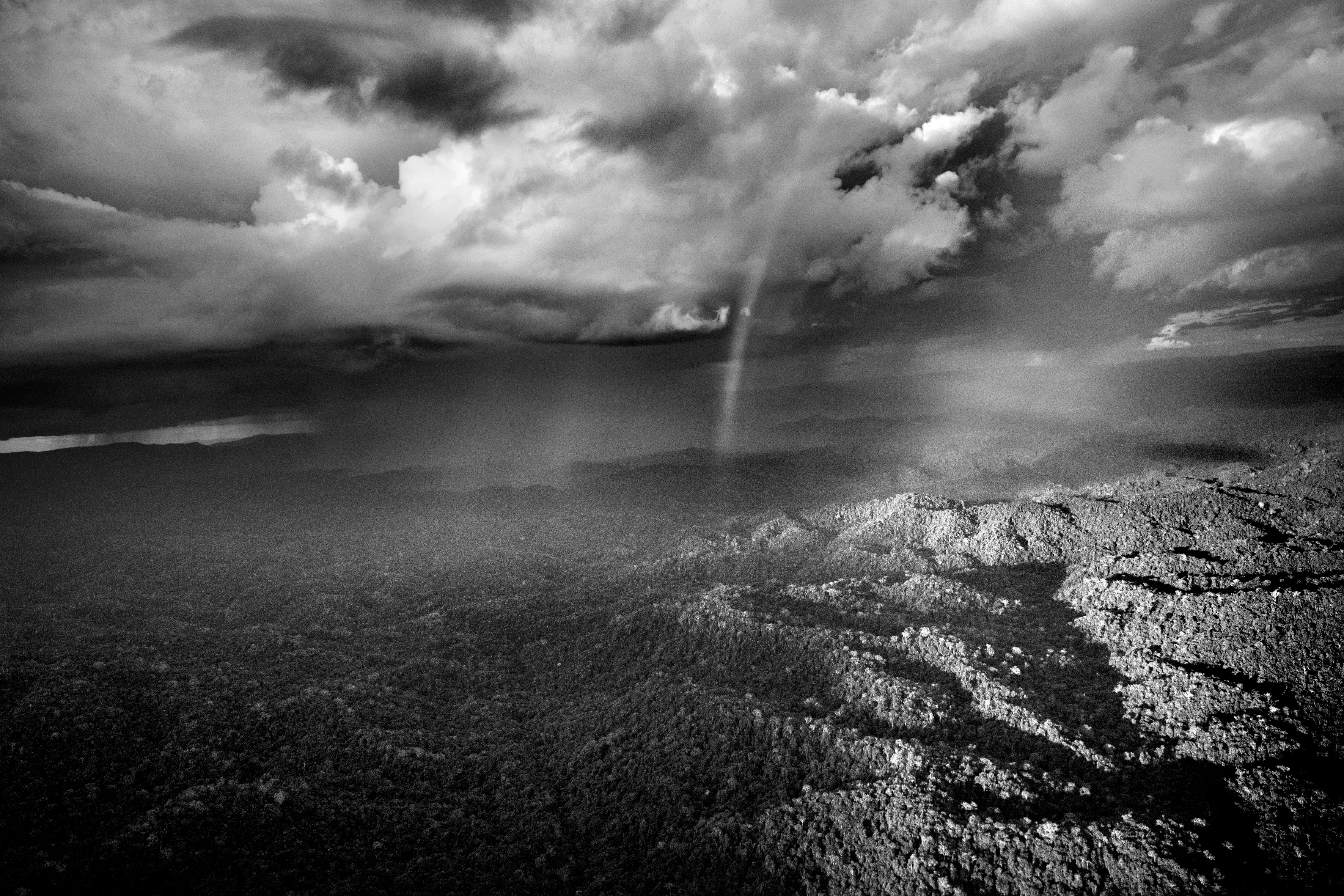 Parima Forest Reserve, State of Roraima, Brazil, 2018

Over the Amazon rainforest, rare is the day when you can see a clear sheet of blue sky or a solid blanket of gray cloud. Rather cloud formations offer an ever-changing spectacle. This begins in the morning when warm moist air rises from the jungle and makes contact with minuscule particles which permit the vapor to condense into water droplets and become little clouds resembling cotton balls known locally as aru. As the day advances, they rise and join forces and, temperature and wind speed permitting, gather strength to become a storm cloud known as a cumulonimbus. This is quite the most dangerous meteorological formation, reaching several thousand meters into the sky, spewing out pieces of ice and winds of up to 200 kilometers per hour (125 miles per hour) at the same time as sending lightning, strong winds, and fierce precipitation toward the jungle. Such is its force that even large aircraft will do everything to avoid it, helicopters immediately look for a jungle clearing in order to land and riverboats hurriedly take shelter from the blinding rain.
