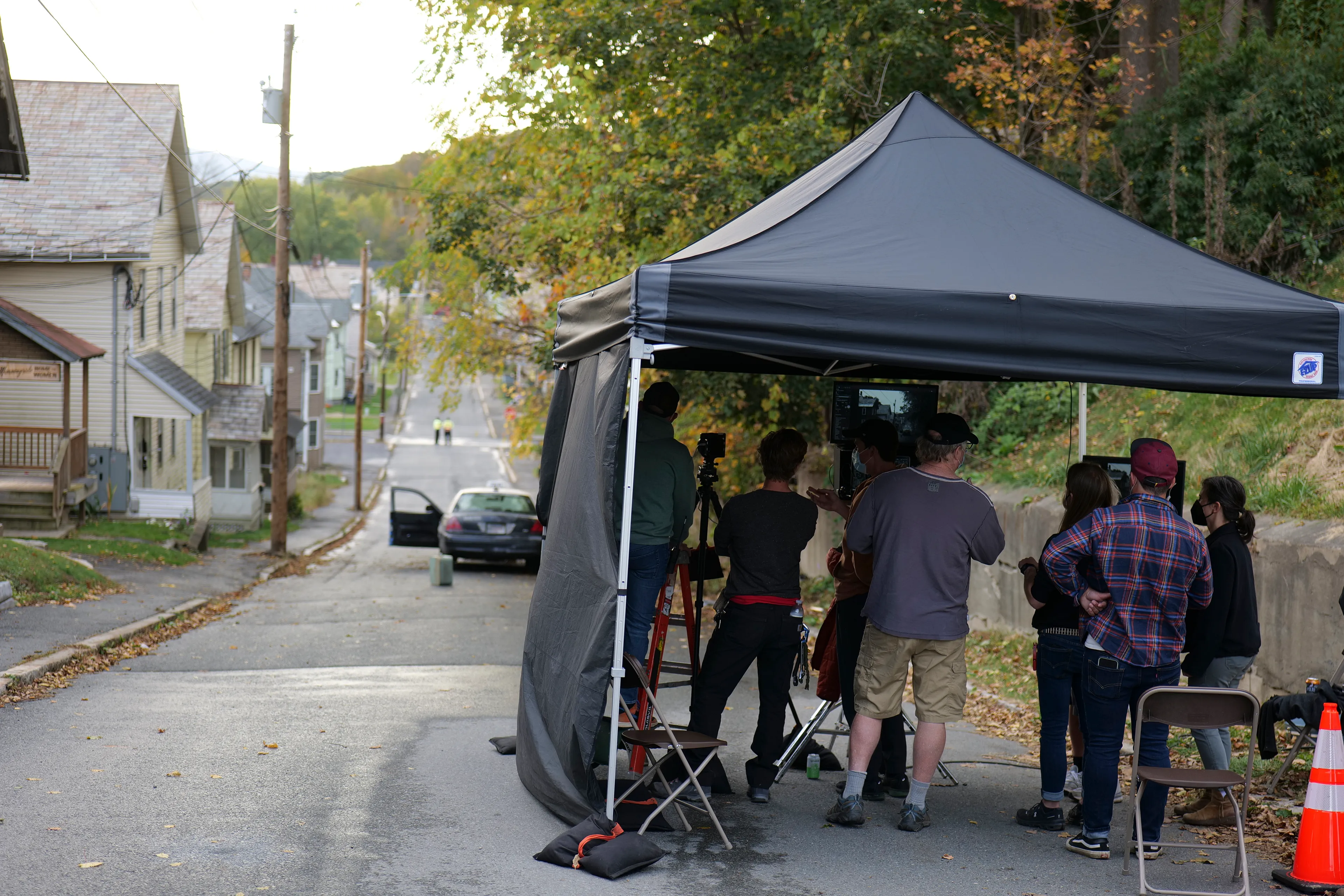 In Eveningside (2021-2022), Crewdson explores moments of contemplation within the confines of quotidien life, in places of employment, and in moments just outside of those work structures. The figures populating the pictures are sparse, and are often seen through storefront windows, in mirror reflections, or positioned underneath the mundane proscenium found in the midst of their everyday routines: railroad bridges, doorways, porches, the overhanging roofline of a bank teller drive-thru, a dairy bar, a corner market, or a hardware store. Bringing his vantage point closer to the figures, using a heightened range of light and darkness, special effects such as fog, rain, smoke, and haze, and for the first time using his now ubiquitous full production and lighting team in a monochromatic palette, the result is a rich gothic atmosphere, evocative of film noir and classic cinema, but with the capabilities and clarity of the most current technology available in digital photography.

Edition: 1 of 1

—

MORNINGSIDE HOME FOR WOMEN 

EXT. MORNINGSIDE - RESIDENTIAL STREET - TWILIGHT

We are standing at the side of a residential street, peering at the houses as they slope downward toward the horizon. Our gaze is mostly concerned with the left hand side of the street, and most prominently, a house covered in faux brick siding. There is a small, barely-legible shingle hanging on the shabby front porch that reads MORNINGSIDE HOME FOR WOMEN.  
 
A TAXI has pulled up on in front of Morningside Home. A TAXI DRIVER sits despondently in the driver's seat, already thinking about his next pickup. A YOUNG WOMAN stands on the sidewalk, having just gotten out. There are a couple old suitcases placed beside her. She looks up at her new home with a sense of trepidation mixed with resignation.