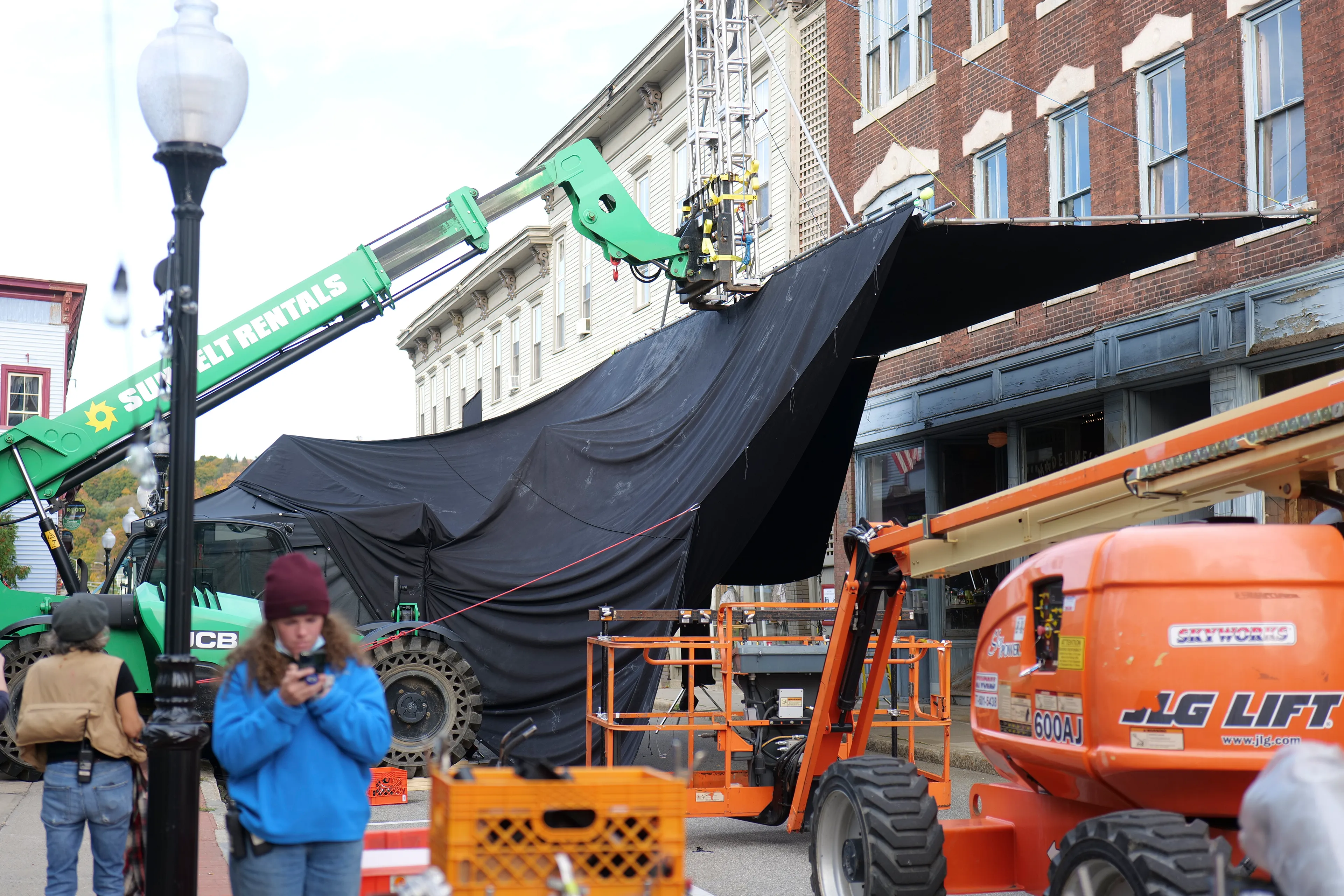 In Eveningside (2021-2022), Crewdson explores moments of contemplation within the confines of quotidien life, in places of employment, and in moments just outside of those work structures. The figures populating the pictures are sparse, and are often seen through storefront windows, in mirror reflections, or positioned underneath the mundane proscenium found in the midst of their everyday routines: railroad bridges, doorways, porches, the overhanging roofline of a bank teller drive-thru, a dairy bar, a corner market, or a hardware store. Bringing his vantage point closer to the figures, using a heightened range of light and darkness, special effects such as fog, rain, smoke, and haze, and for the first time using his now ubiquitous full production and lighting team in a monochromatic palette, the result is a rich gothic atmosphere, evocative of film noir and classic cinema, but with the capabilities and clarity of the most current technology available in digital photography.

Edition: 1 of 1

—

MADELINE'S BEAUTY SALON

EXT. EVENINGSIDE - MADELINE'S BEAUTY SALON - TWILIGHT 

We are standing outside a storefront, late in the day. We can just see part of the sidewalk out front, and a touch of the brick building above. Our main focus is the large window of a hair salon, and the stoop just beside it. 

The building is very weathered, with once beautiful architectural details. Wood paneling surrounds the doorways and windows. There is faded lettering on the top of the window that says MADELINE'S BEAUTY SALON. 

Through the window, we can see a YOUNG WOMAN seated in the chair having her hair cut. A WOMAN having an air of sophistication and formality about her, something classic and timeless in her appearance, whom we might assume is the namesake Madeline, is standing behind her. They are both reflected back in the mirror, but Madeline seems lost in thought as she sees something of herself in the younger woman's face.