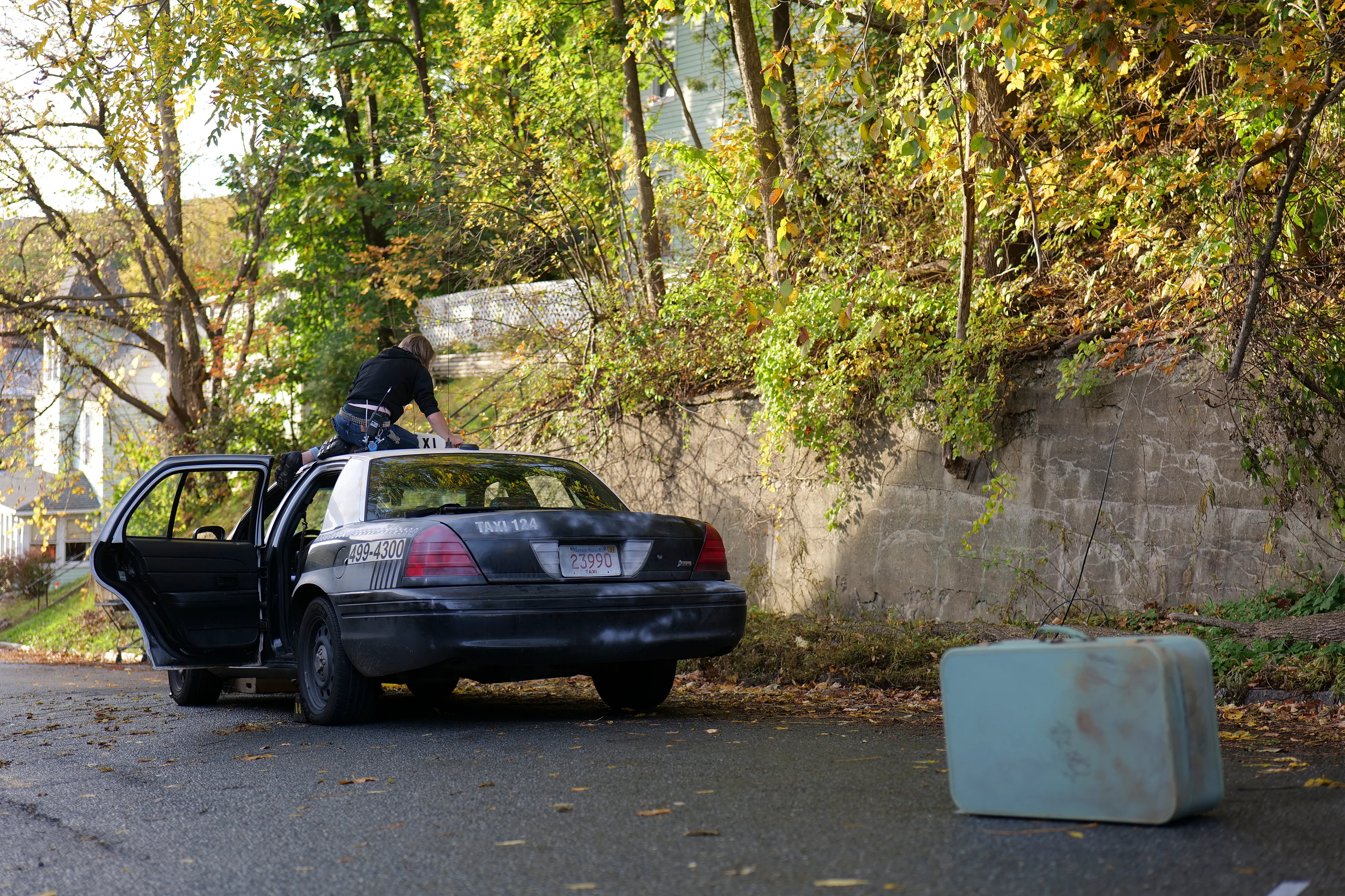 In Eveningside (2021-2022), Crewdson explores moments of contemplation within the confines of quotidien life, in places of employment, and in moments just outside of those work structures. The figures populating the pictures are sparse, and are often seen through storefront windows, in mirror reflections, or positioned underneath the mundane proscenium found in the midst of their everyday routines: railroad bridges, doorways, porches, the overhanging roofline of a bank teller drive-thru, a dairy bar, a corner market, or a hardware store. Bringing his vantage point closer to the figures, using a heightened range of light and darkness, special effects such as fog, rain, smoke, and haze, and for the first time using his now ubiquitous full production and lighting team in a monochromatic palette, the result is a rich gothic atmosphere, evocative of film noir and classic cinema, but with the capabilities and clarity of the most current technology available in digital photography.

Edition: 1 of 1

—

MORNINGSIDE HOME FOR WOMEN 

EXT. MORNINGSIDE - RESIDENTIAL STREET - TWILIGHT

We are standing at the side of a residential street, peering at the houses as they slope downward toward the horizon. Our gaze is mostly concerned with the left hand side of the street, and most prominently, a house covered in faux brick siding. There is a small, barely-legible shingle hanging on the shabby front porch that reads MORNINGSIDE HOME FOR WOMEN.  
 
A TAXI has pulled up on in front of Morningside Home. A TAXI DRIVER sits despondently in the driver's seat, already thinking about his next pickup. A YOUNG WOMAN stands on the sidewalk, having just gotten out. There are a couple old suitcases placed beside her. She looks up at her new home with a sense of trepidation mixed with resignation.