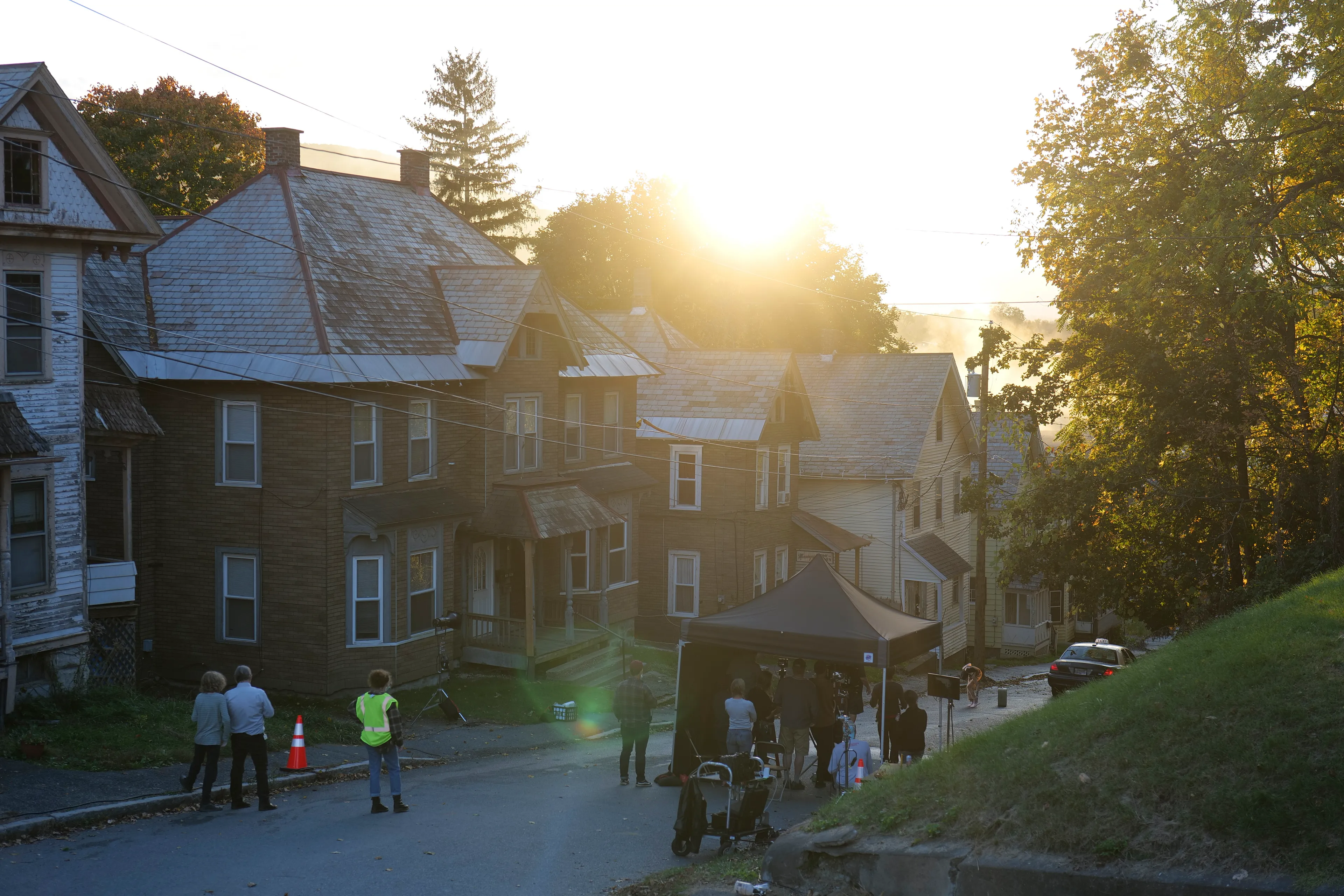 In Eveningside (2021-2022), Crewdson explores moments of contemplation within the confines of quotidien life, in places of employment, and in moments just outside of those work structures. The figures populating the pictures are sparse, and are often seen through storefront windows, in mirror reflections, or positioned underneath the mundane proscenium found in the midst of their everyday routines: railroad bridges, doorways, porches, the overhanging roofline of a bank teller drive-thru, a dairy bar, a corner market, or a hardware store. Bringing his vantage point closer to the figures, using a heightened range of light and darkness, special effects such as fog, rain, smoke, and haze, and for the first time using his now ubiquitous full production and lighting team in a monochromatic palette, the result is a rich gothic atmosphere, evocative of film noir and classic cinema, but with the capabilities and clarity of the most current technology available in digital photography.

Edition: 1 of 1

—

MORNINGSIDE HOME FOR WOMEN 

EXT. MORNINGSIDE - RESIDENTIAL STREET - TWILIGHT

We are standing at the side of a residential street, peering at the houses as they slope downward toward the horizon. Our gaze is mostly concerned with the left hand side of the street, and most prominently, a house covered in faux brick siding. There is a small, barely-legible shingle hanging on the shabby front porch that reads MORNINGSIDE HOME FOR WOMEN.  
 
A TAXI has pulled up on in front of Morningside Home. A TAXI DRIVER sits despondently in the driver's seat, already thinking about his next pickup. A YOUNG WOMAN stands on the sidewalk, having just gotten out. There are a couple old suitcases placed beside her. She looks up at her new home with a sense of trepidation mixed with resignation.