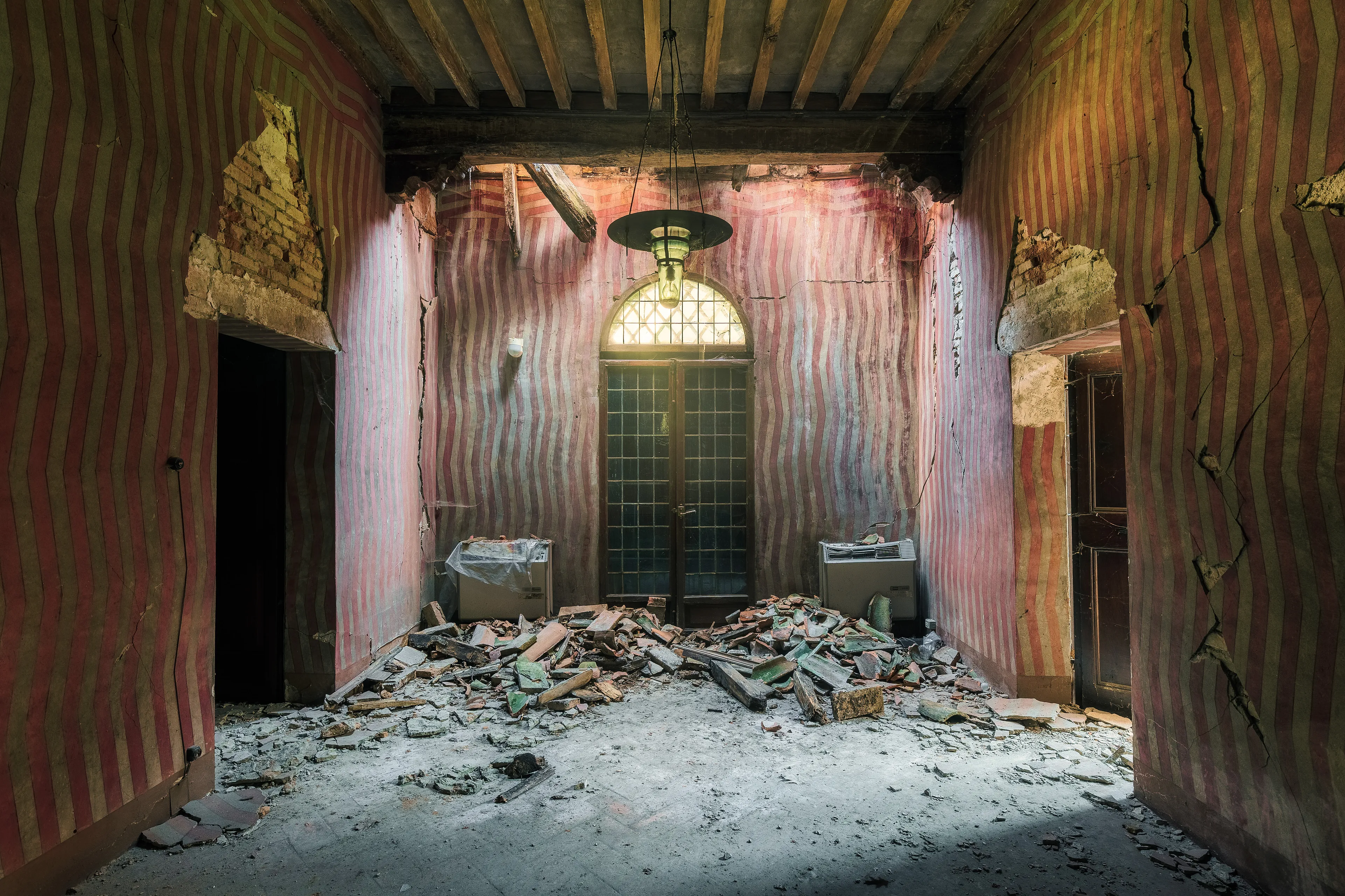 The Italians have always been known for their murals. This mural, however, is very atypical and yet fascinating when you consider that it is painted. The slight curvature of the walls, caused by an earthquake, gave the scene almost a kind of 3D effect. 
Today, this part of the building has collapsed and this photograph is a last witness to this obscure scene.